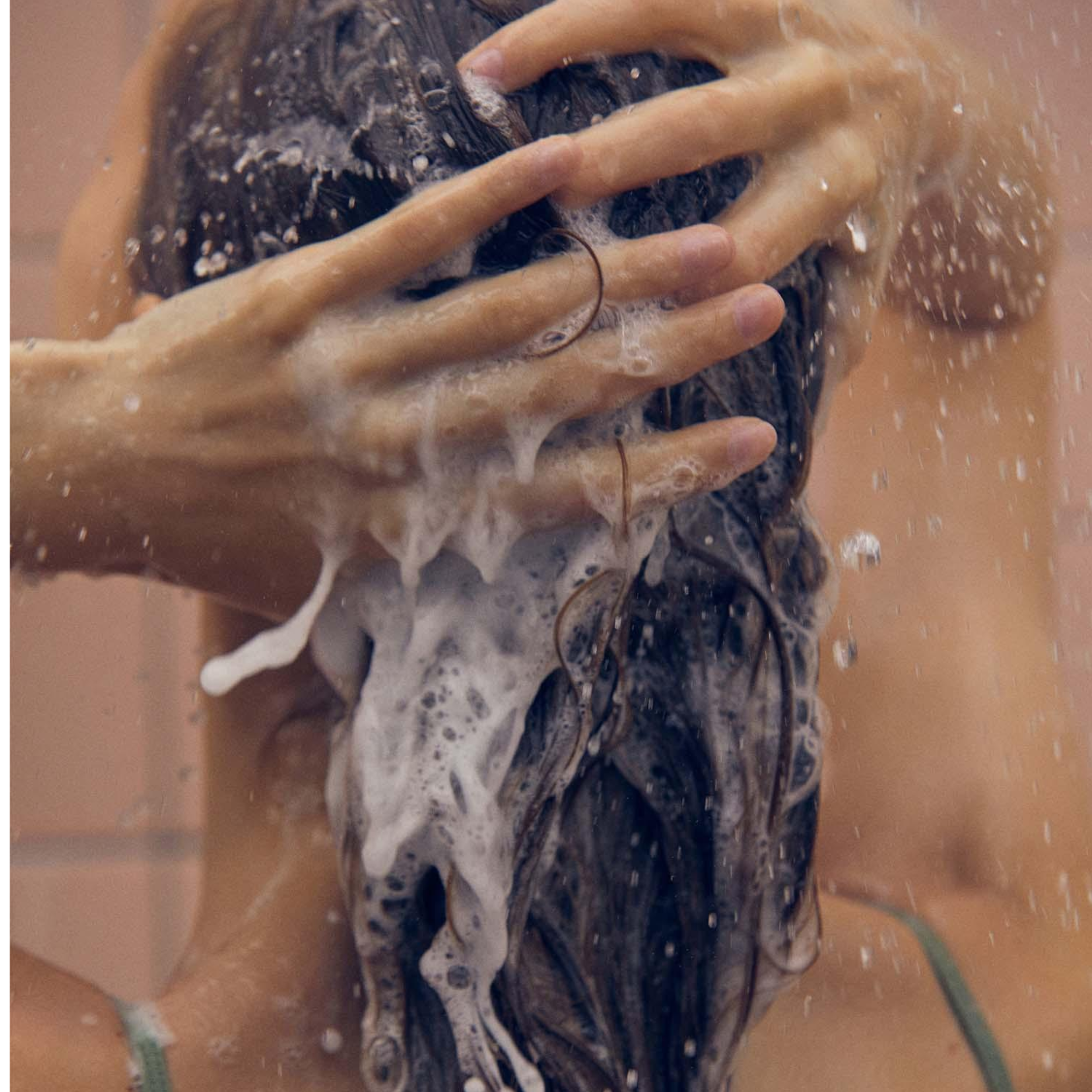 Person washing hair with soapy water in a shower setting