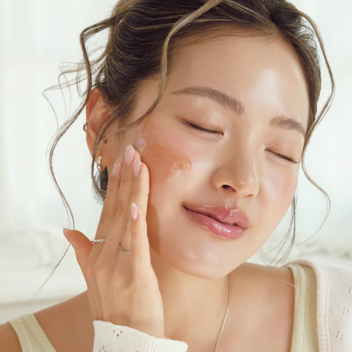 Woman applying cream to her face with a soft background