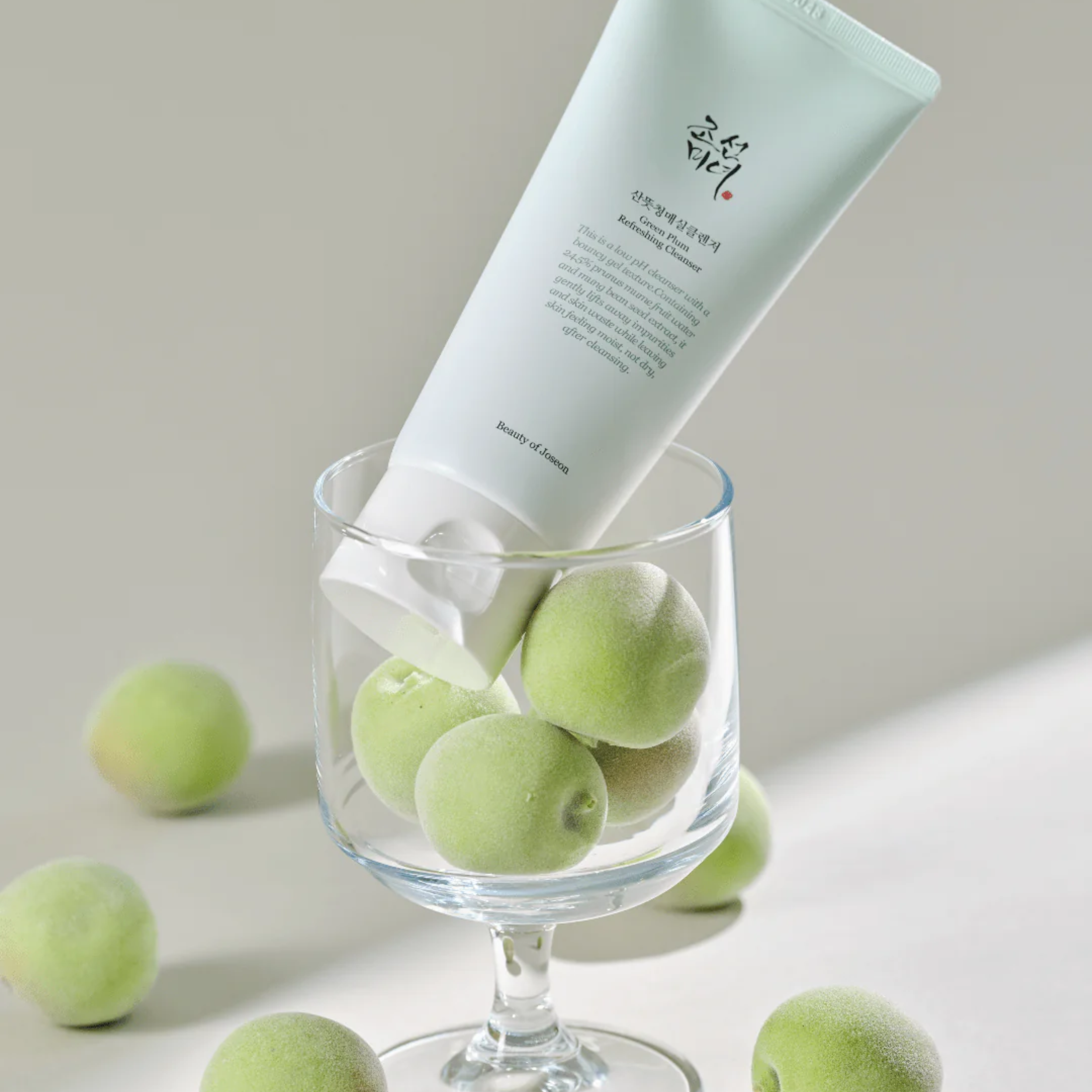 Tube of cream in a glass with green fruits on a neutral background