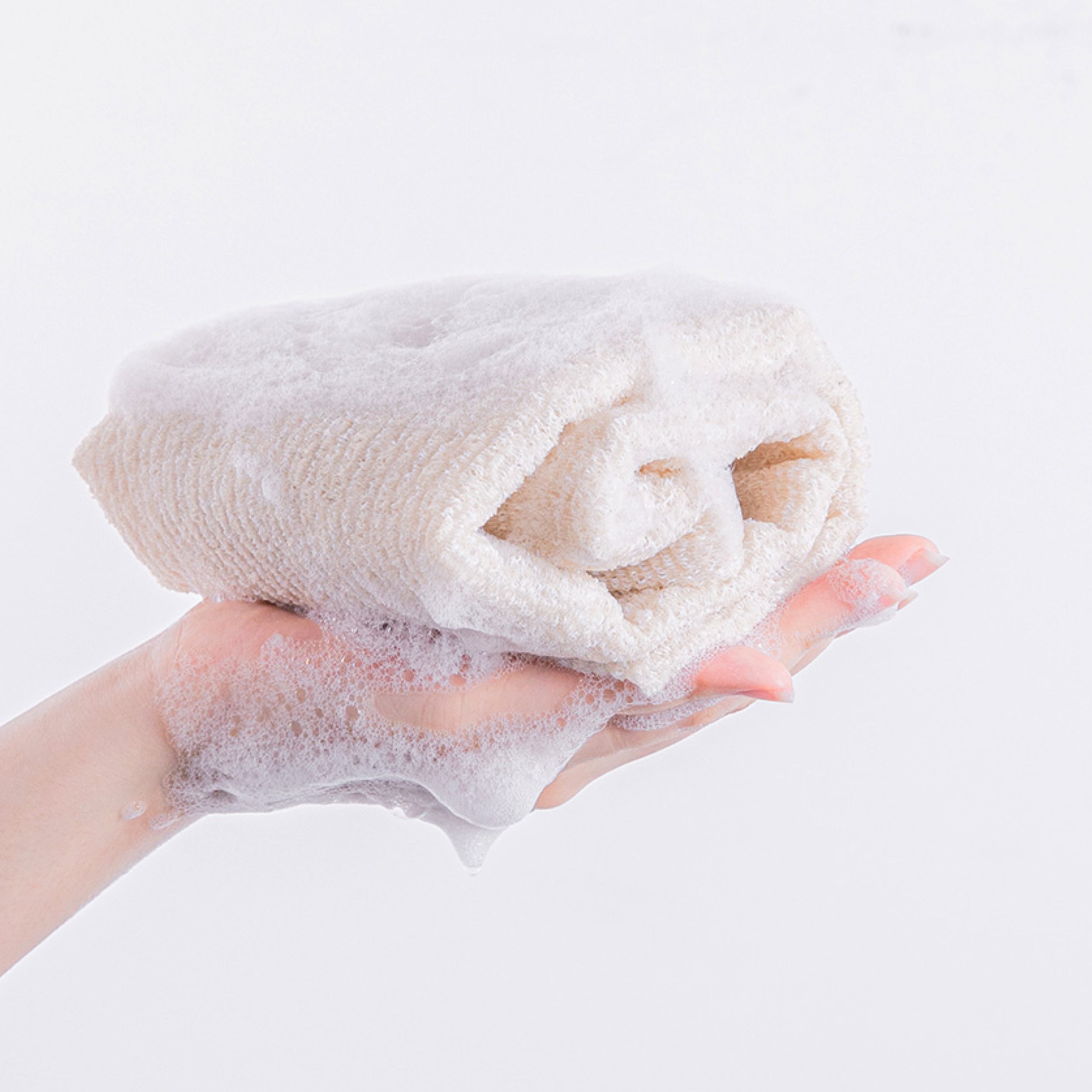 Hand holding a fluffy white towel with soap suds on a light gray background