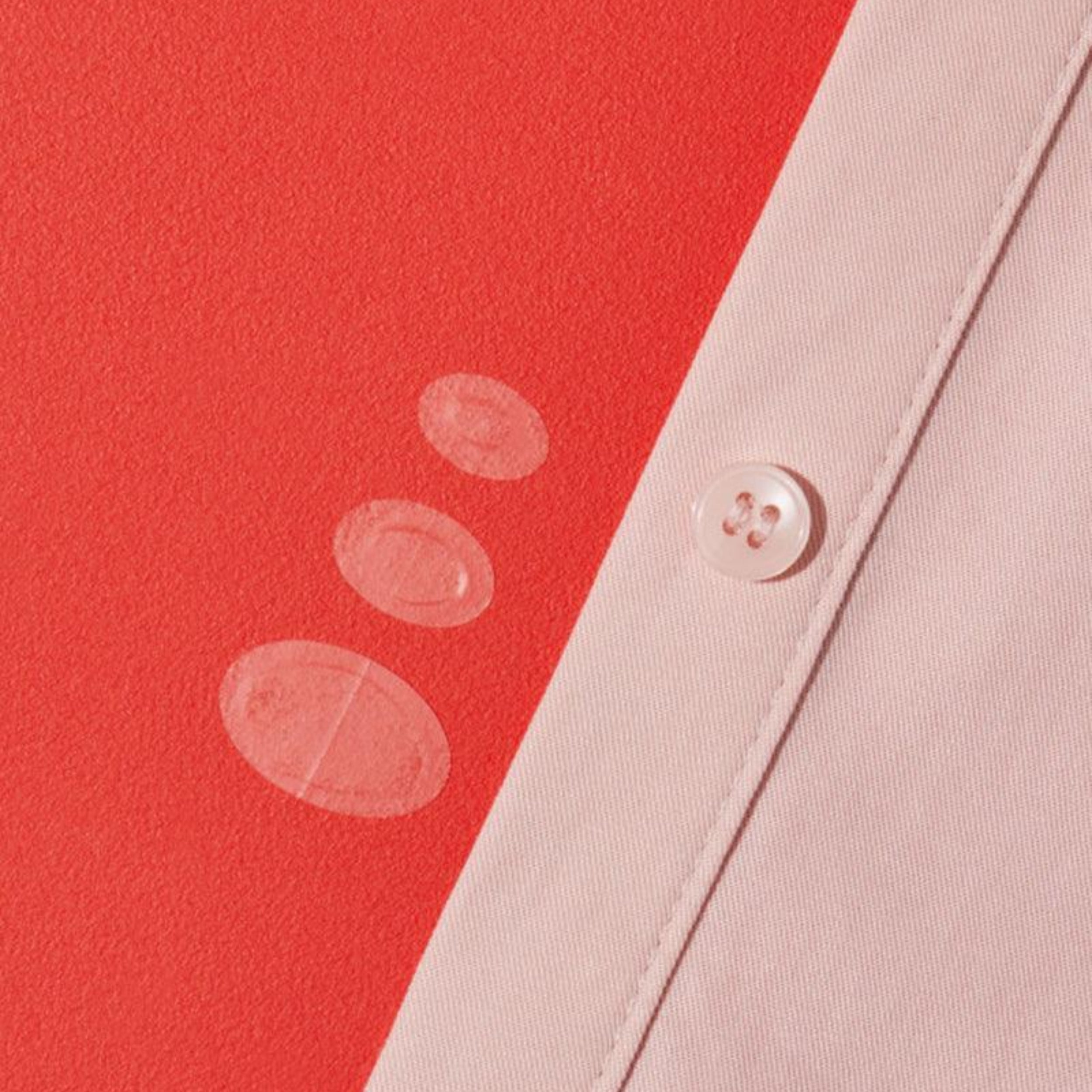 Close-up of a button on a light pink fabric against a red background