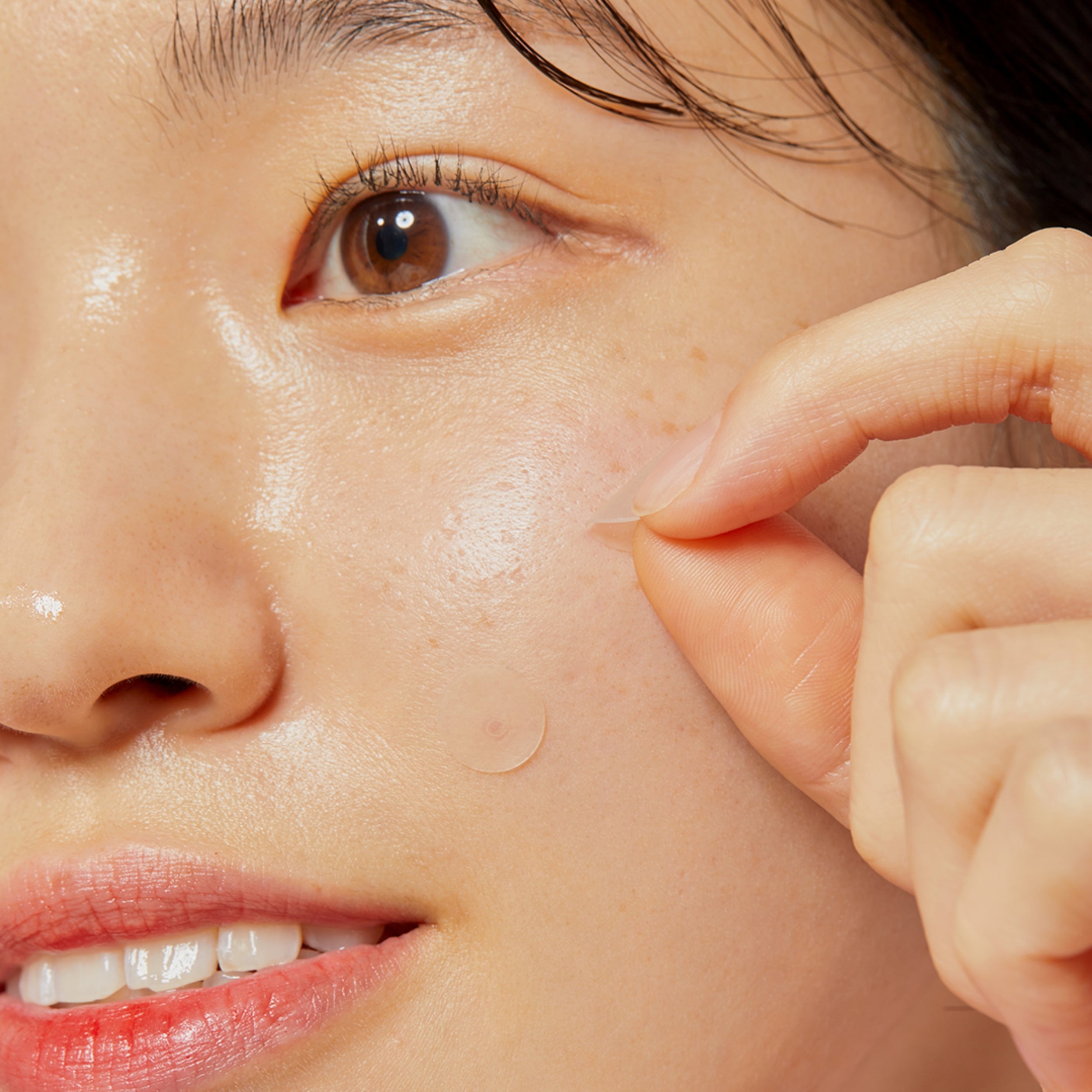 Close-up of a person pointing to a blemish on their face.