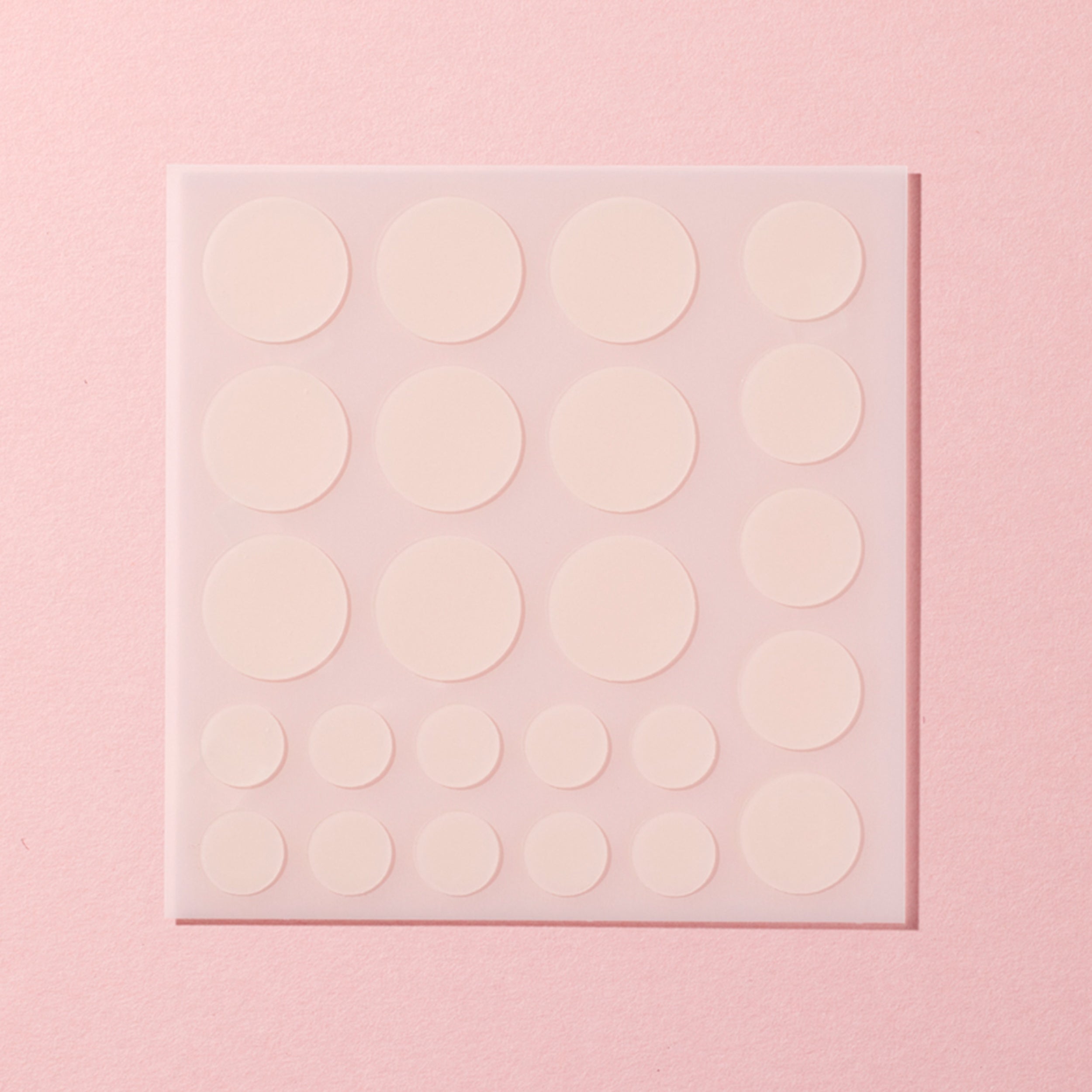 Sheet of round white stickers on a pink background