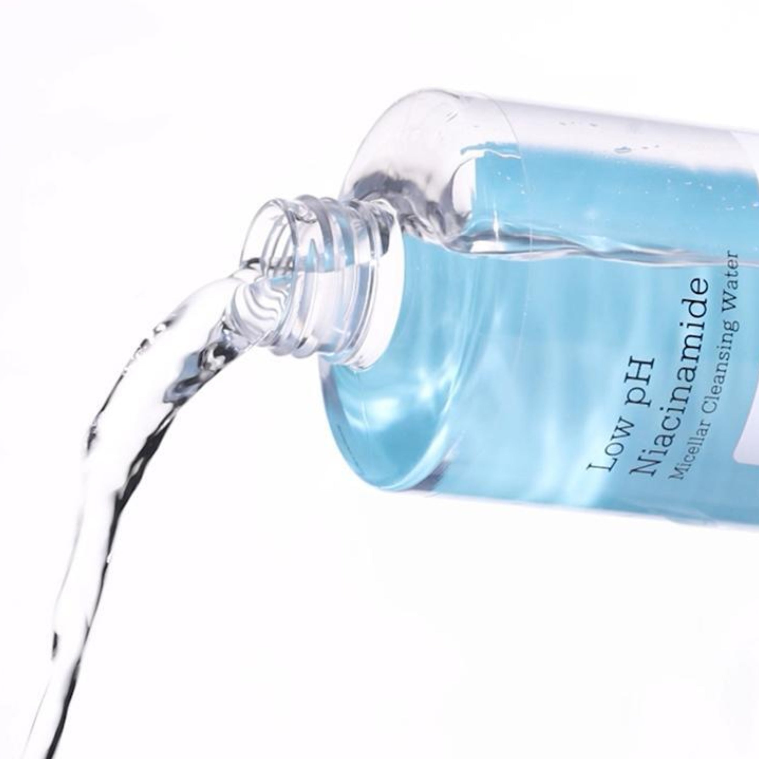 Bottle of Low pH Niacinamide Micellar Cleansing Water being poured on a white background