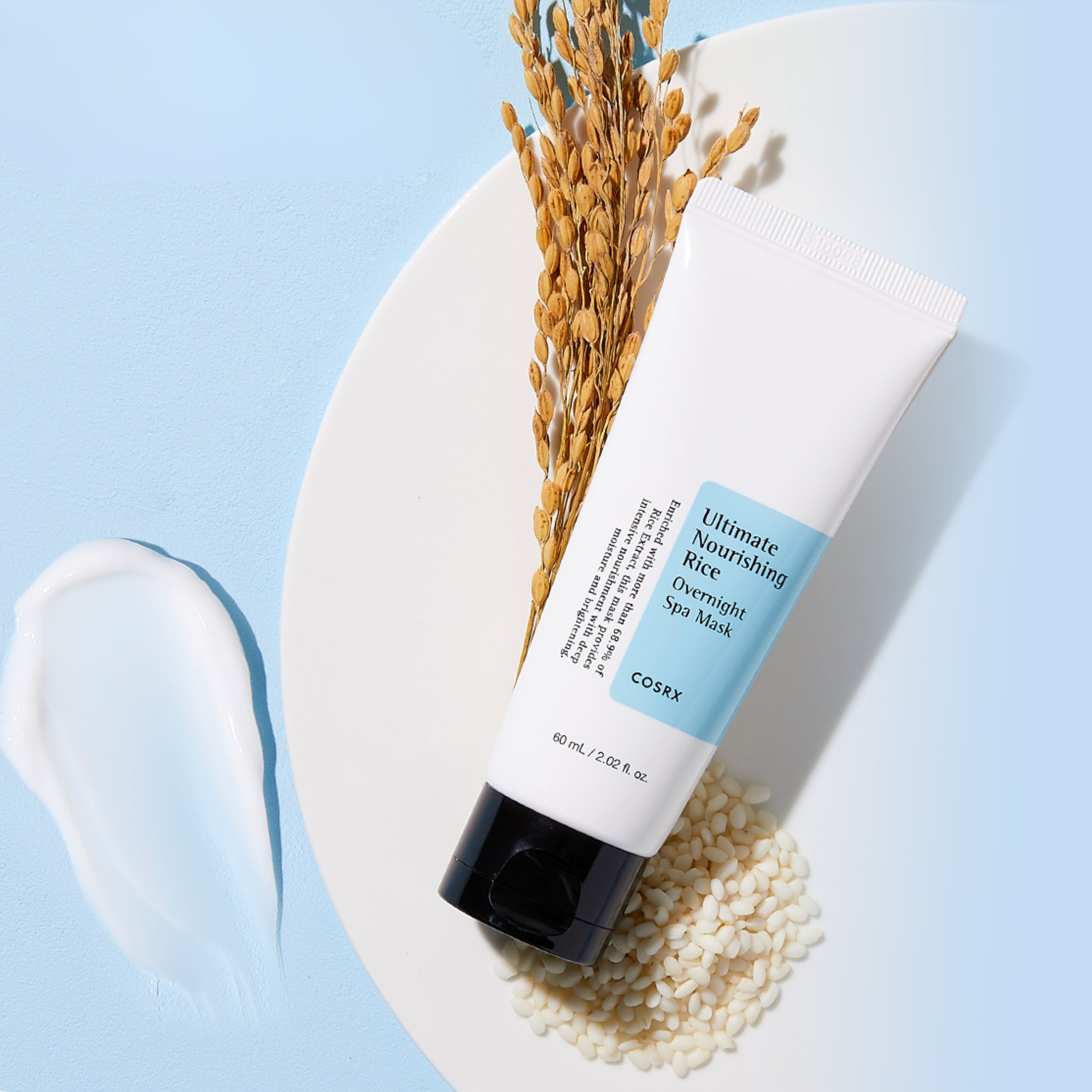 CosRX Ultimate Nourishing Rice Overnight Spa Mask on a light blue background with rice grains and a white plate.