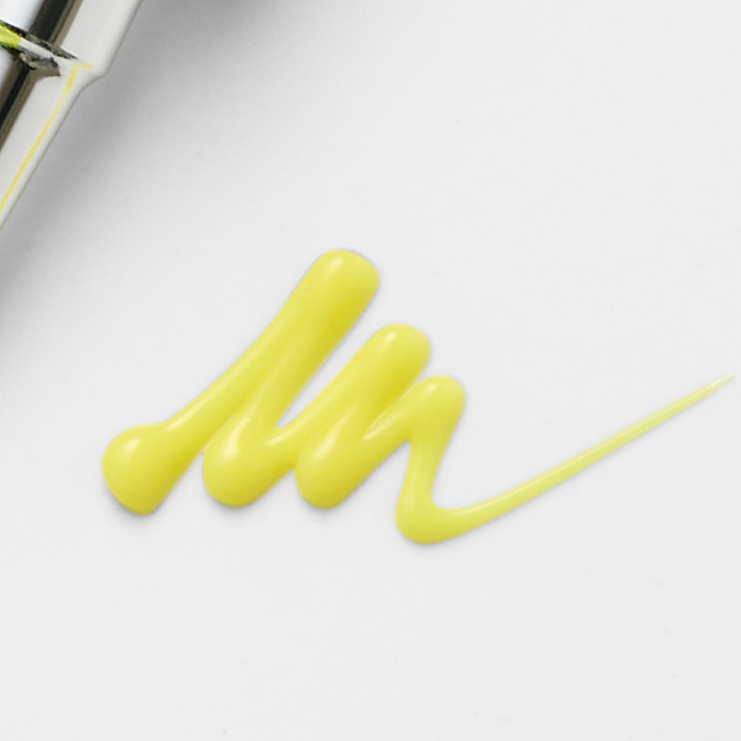Close-up of yellow nail polish being applied with a brush on a white background