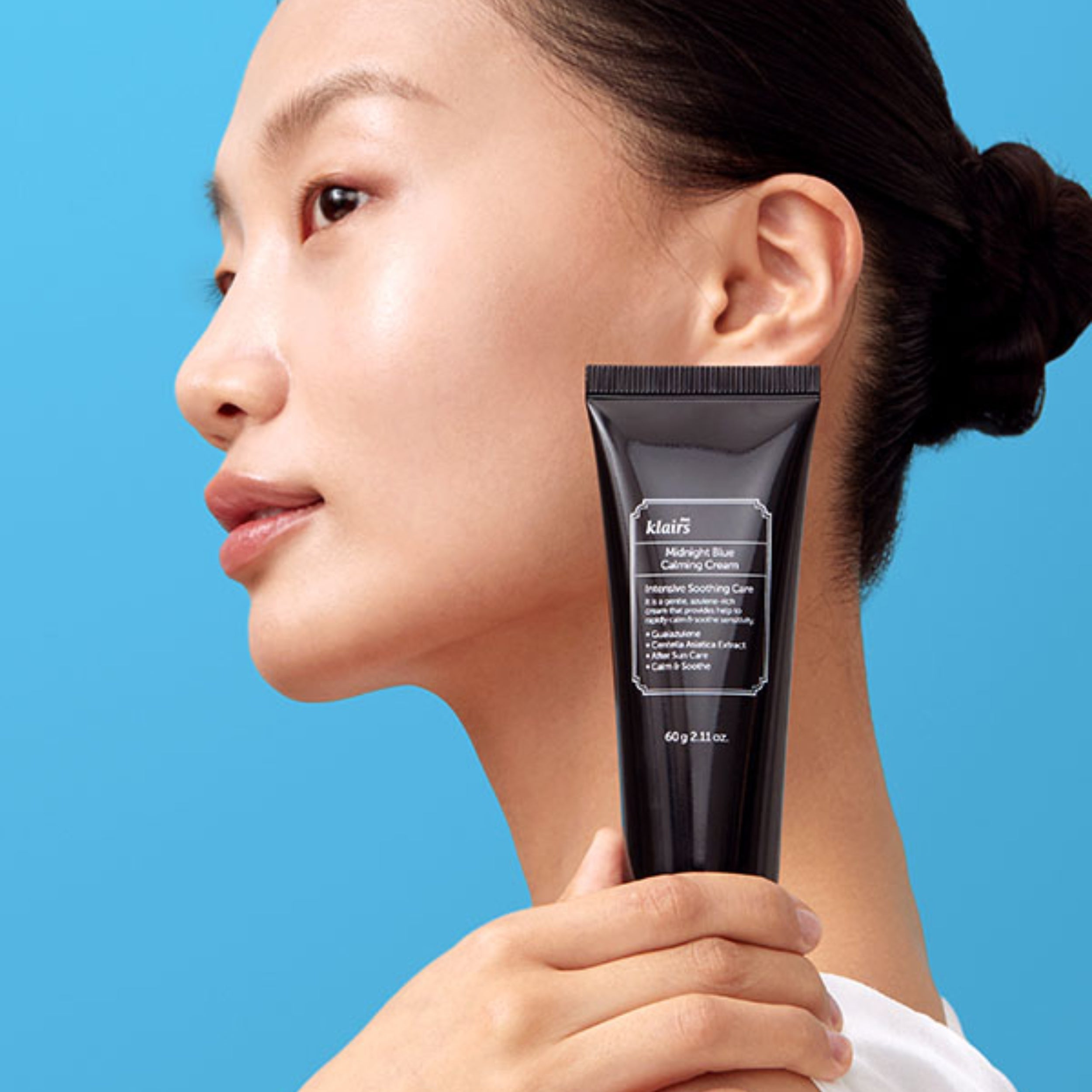 Woman holding a Kiehl's skincare product against a blue background