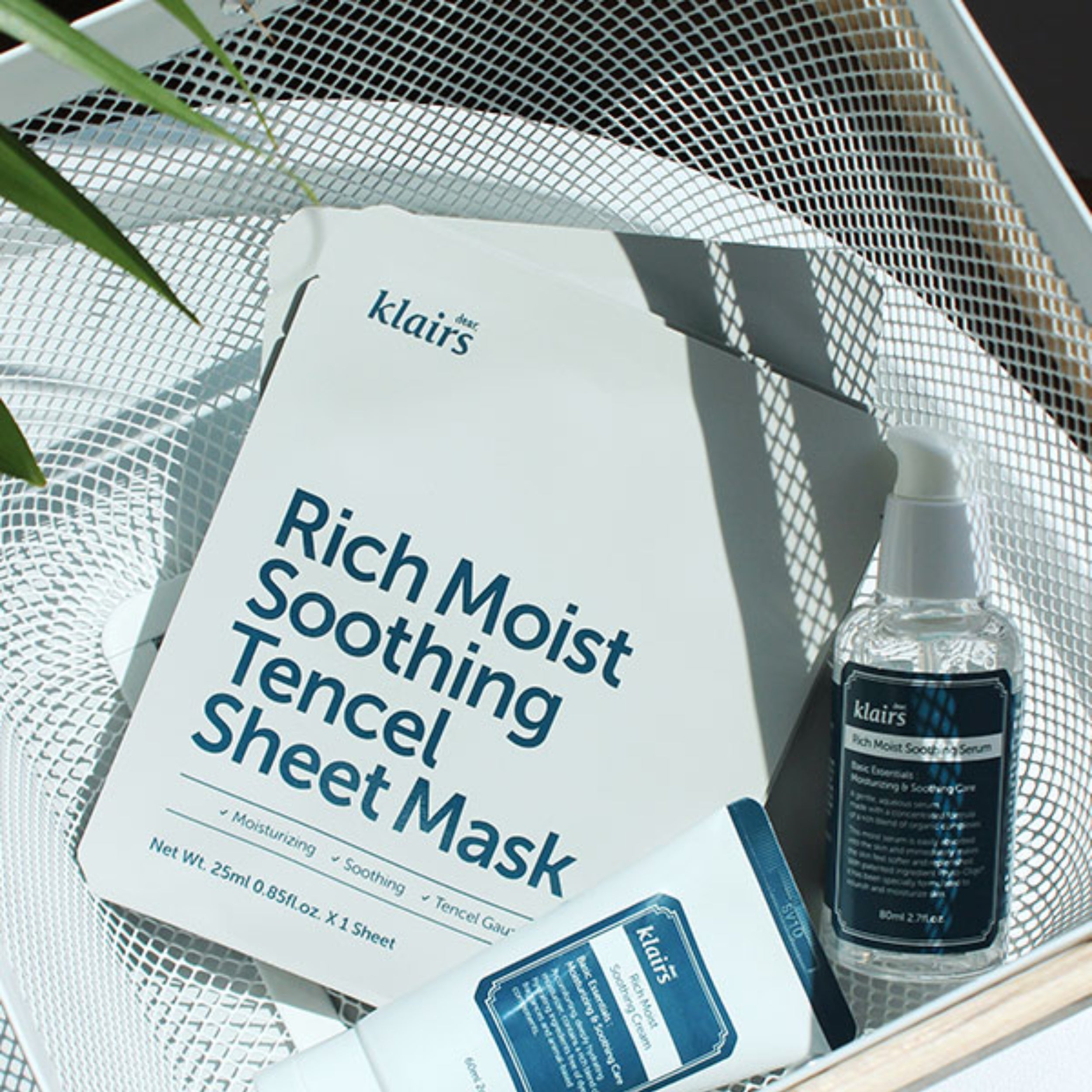 Klairs Rich Moist Soothing Tencel Sheet Mask and serum bottle on a textured surface