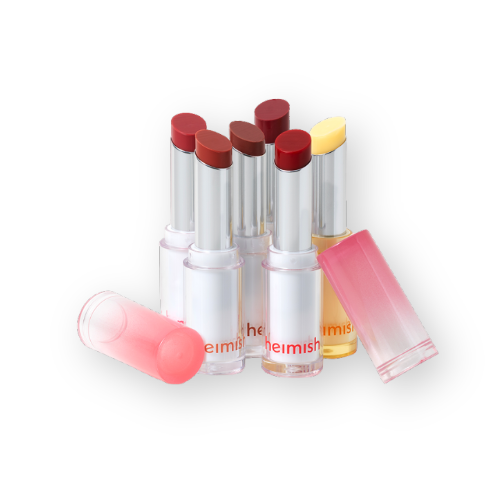 A group of Heimish lipsticks and lip balm tubes arranged on a white background. Several tubes are open, showing deep berry-red and coral-pink balm colors, while others are closed in translucent pink and pale yellow cases.