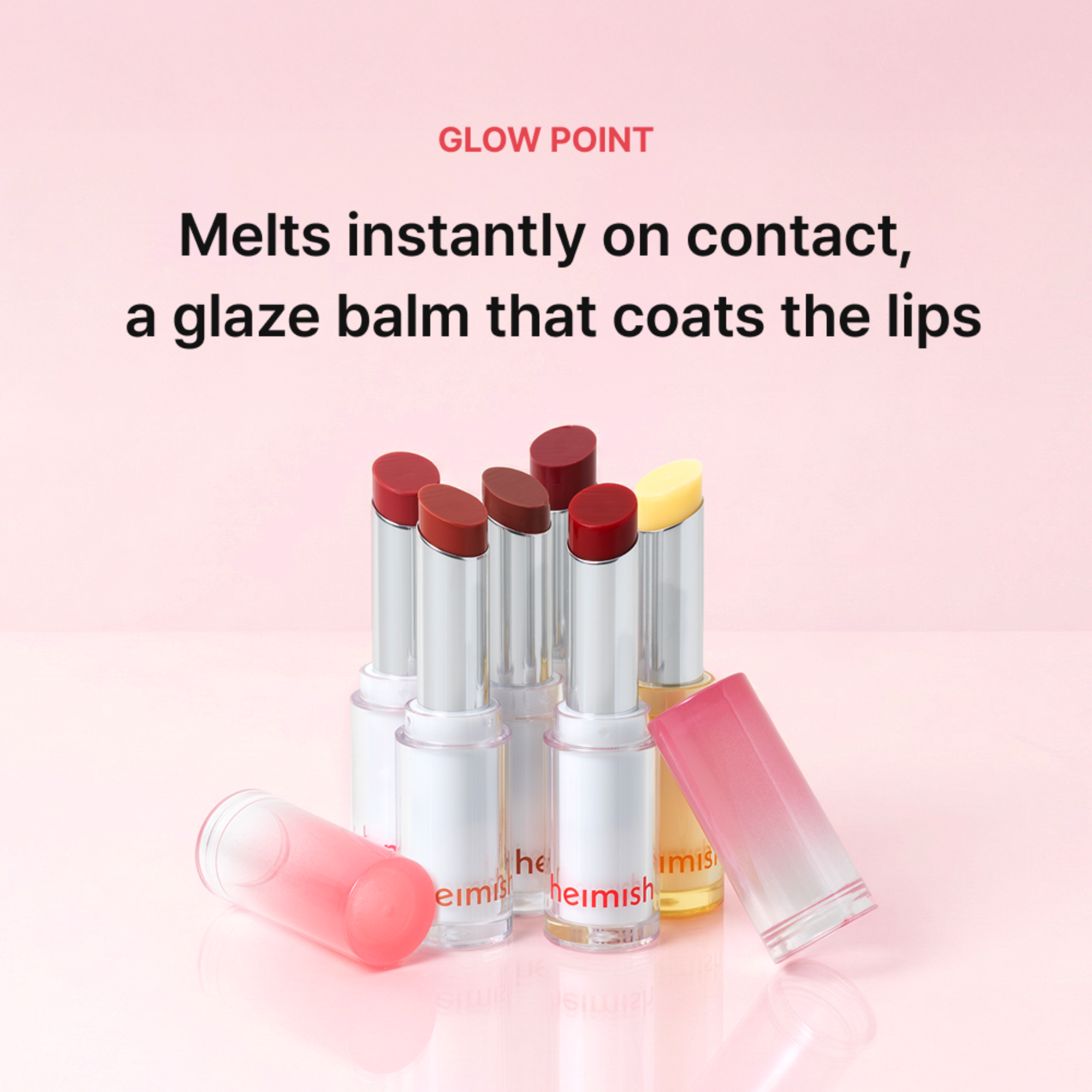 Six lip products from Heimish arranged on a soft pink studio background with promotional text above. The products include several lipstick tubes in dark red and brown shades, a yellow-toned tube, and a pink-to-clear gloss stick lying on its side.