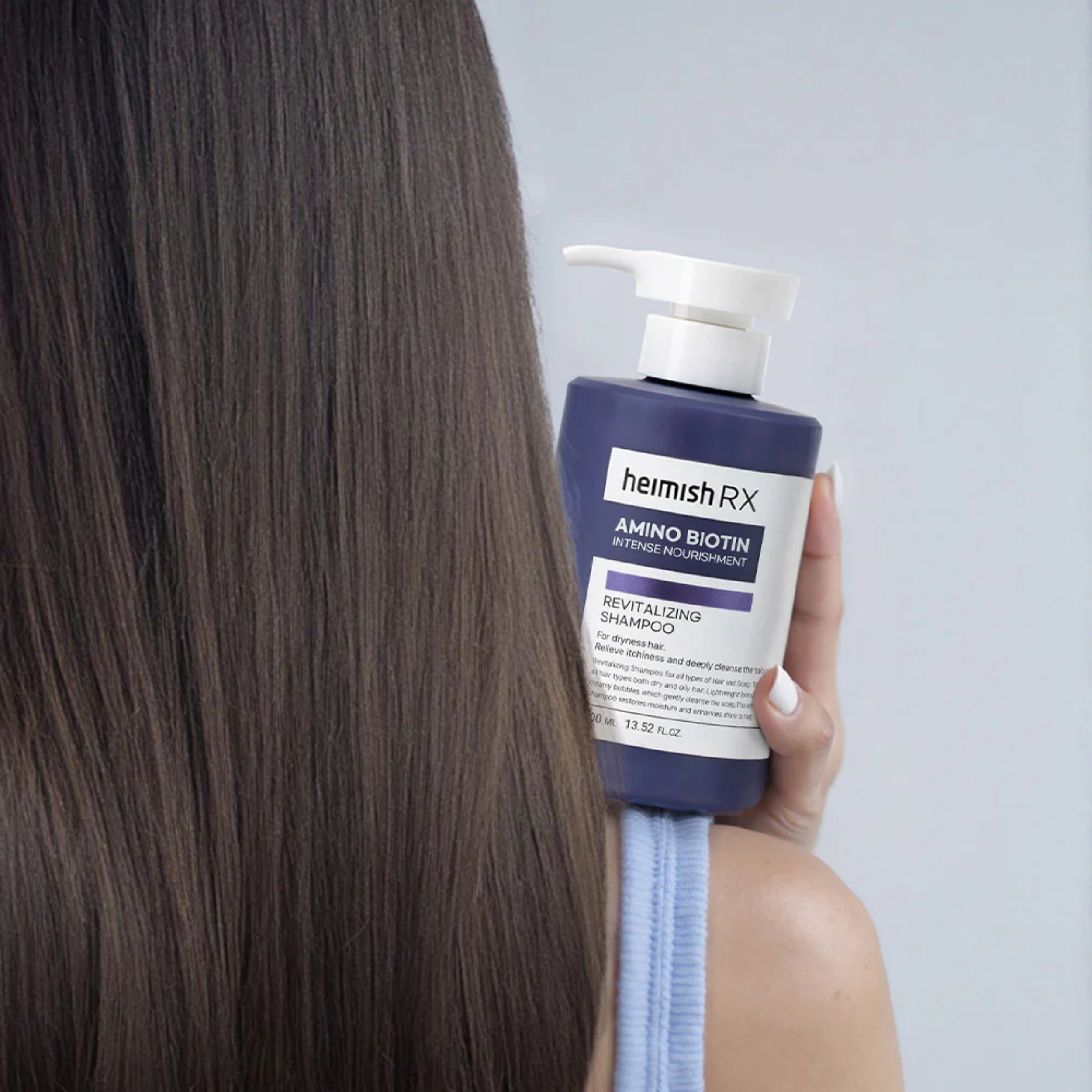 Person holding a bottle of heimish RX shampoo with long hair in the foreground