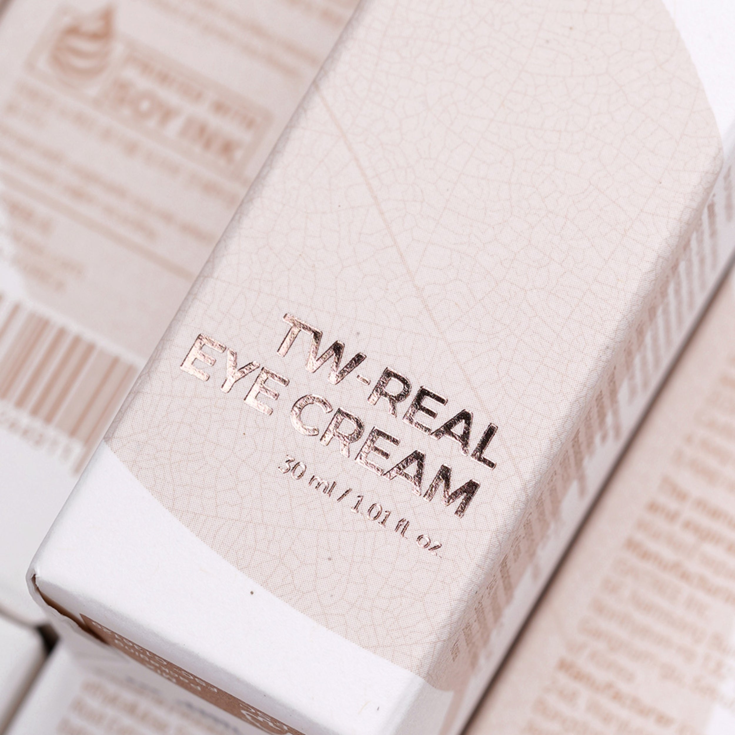 Close-up of a skincare product packaging with 'TW. Real Eye Cream' text.