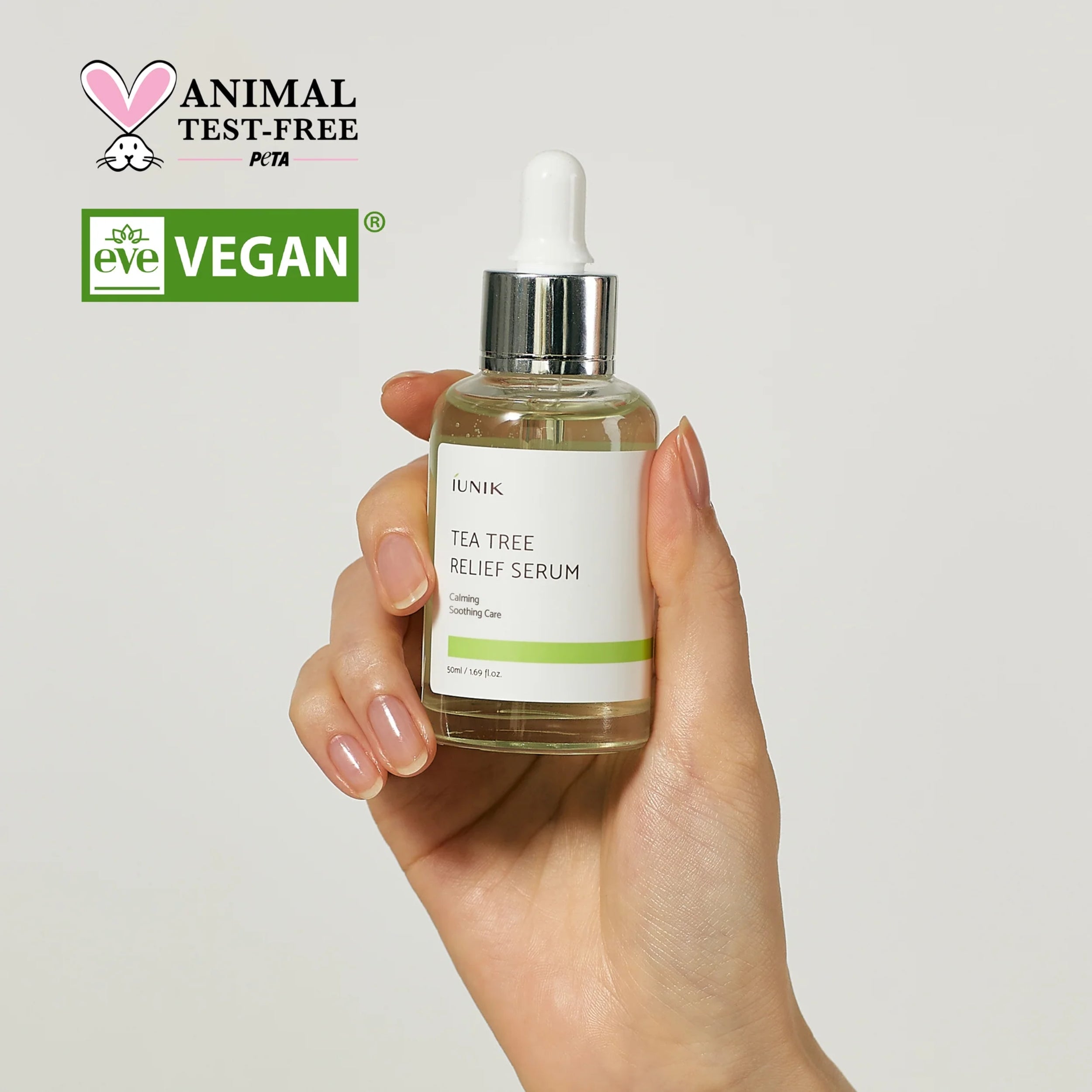 Hand holding a bottle of 'Tea Tree Relief Serum' with PETA and Eve Vegan logos on a light gray background.
