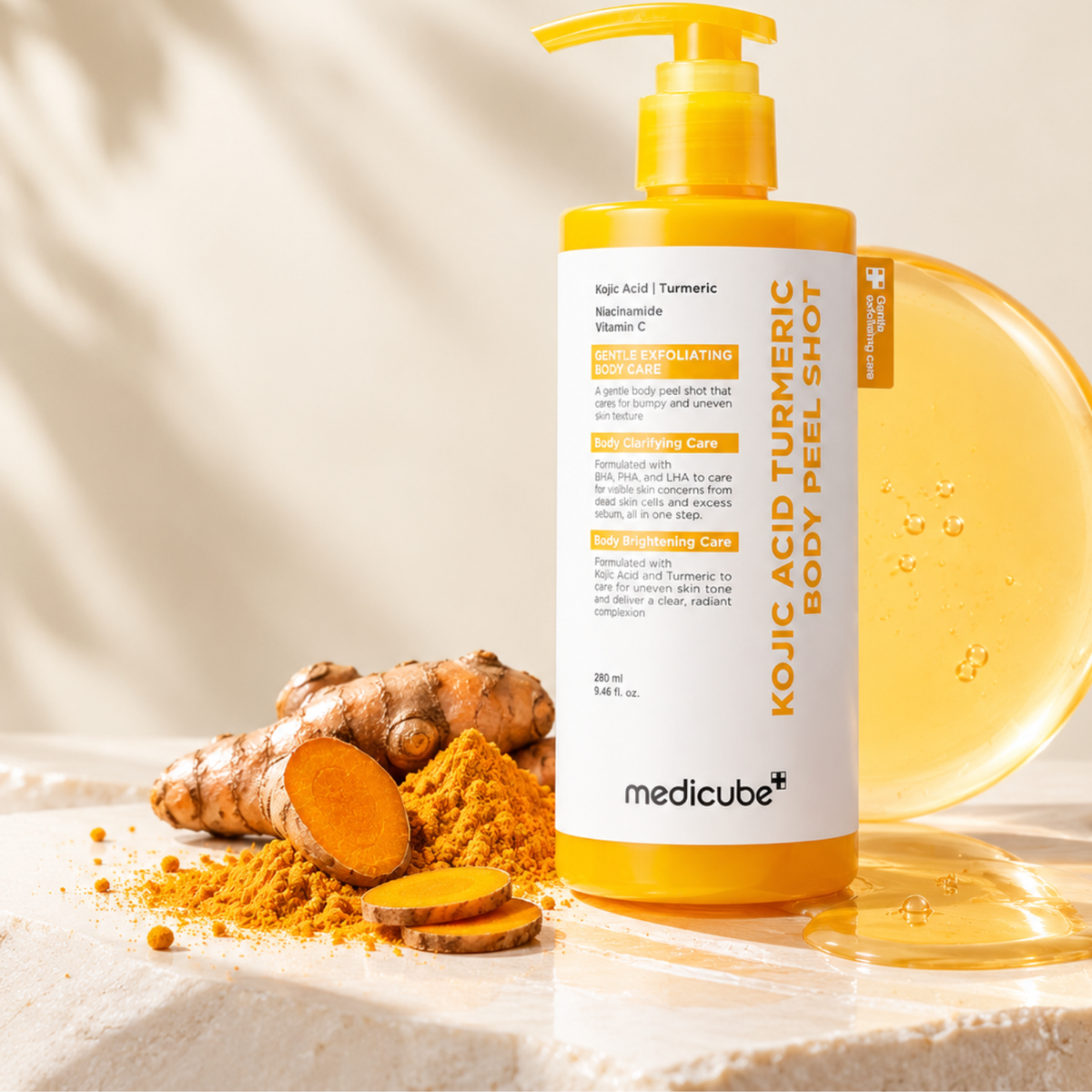 A bottle of medicube Kojic Acid Turmeric Body Peel Shot stands on a light stone surface with turmeric root, slices, and powder nearby, plus a translucent honey-colored gel dish behind it.