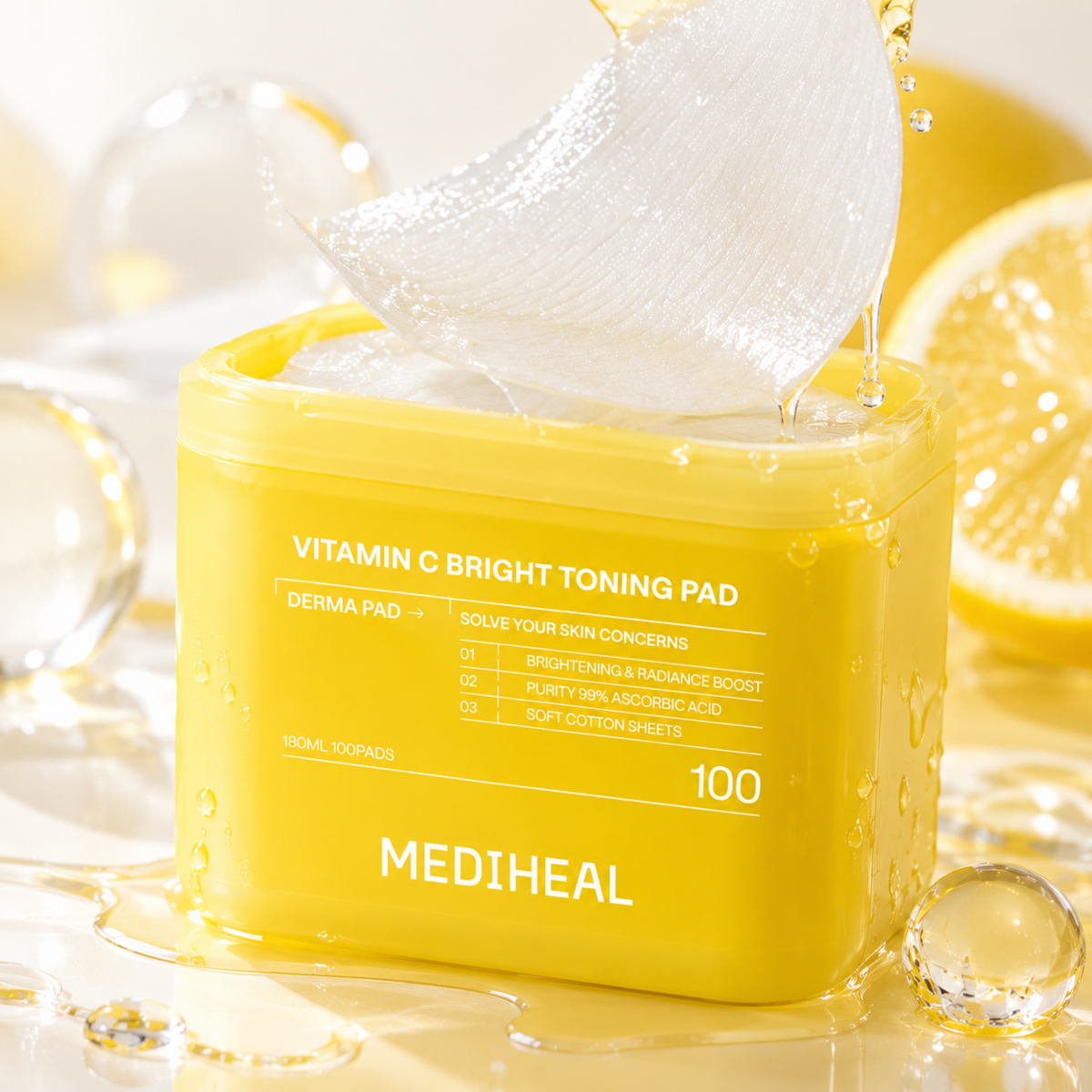A yellow MEDIHEAL Vitamin C Bright Toning Pad jar with a translucent sheet being pulled out from the top, surrounded by lemon slices, clear glass spheres, and liquid droplets on a bright white background.