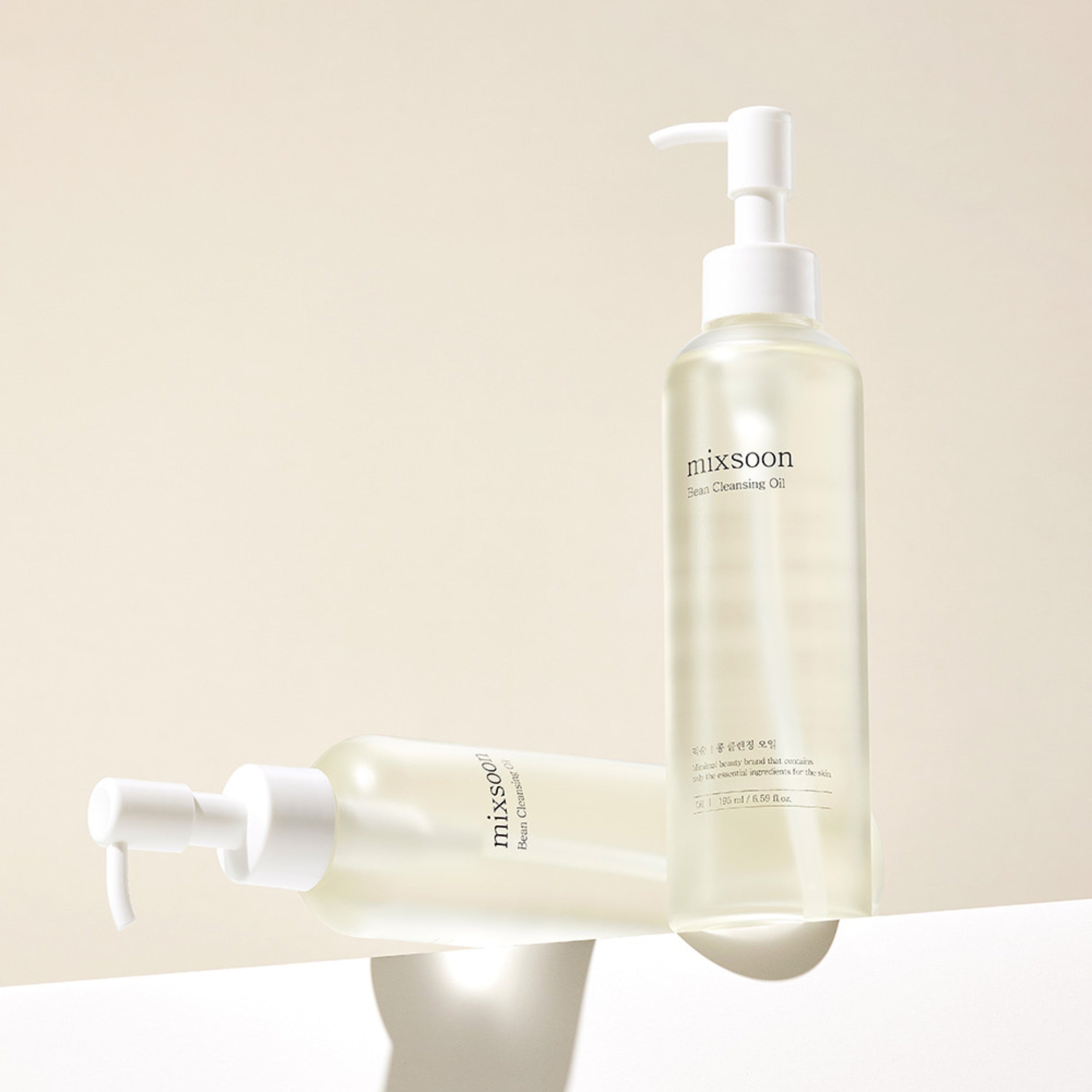 Two bottles of 'mixsoon' facial cleansing oil on a beige background