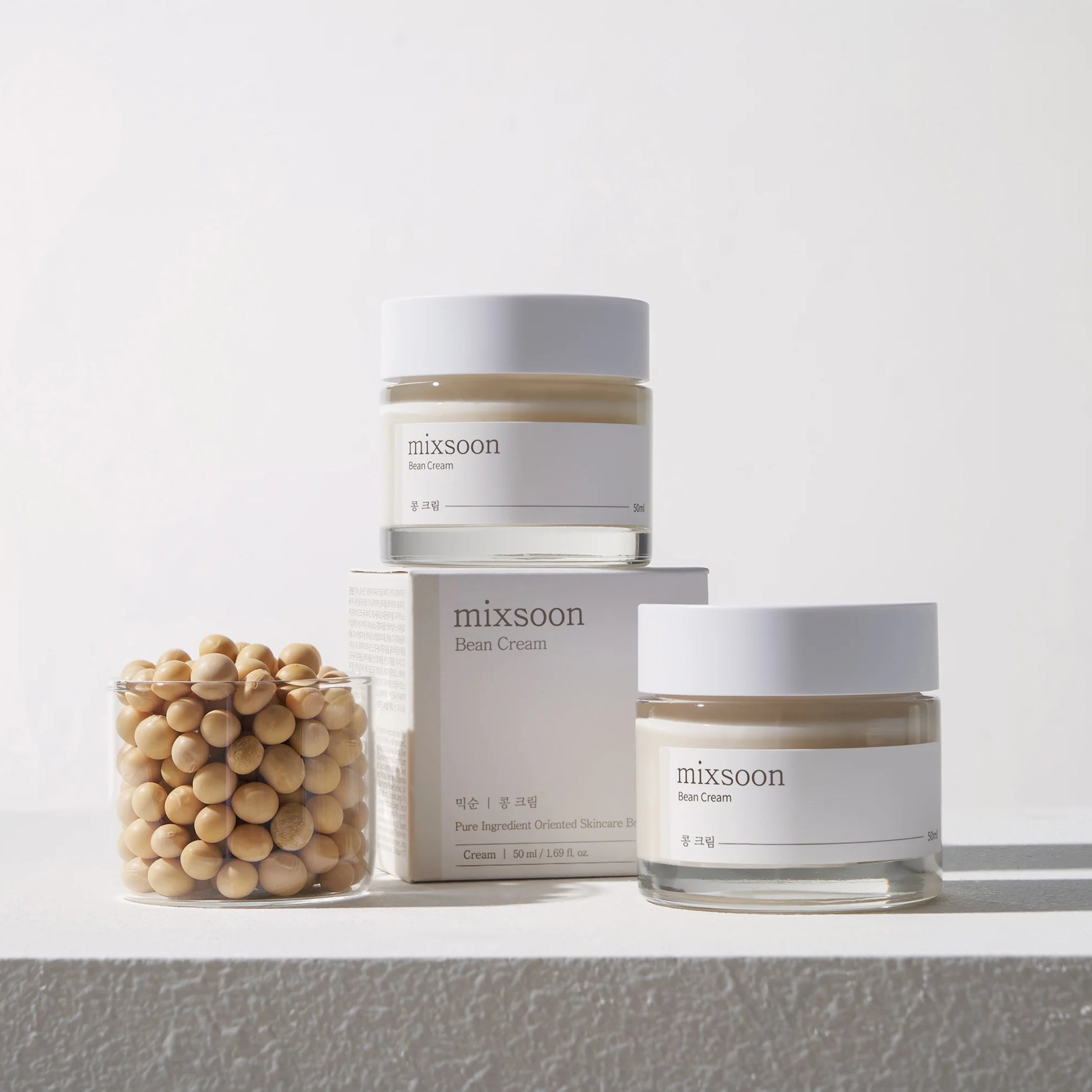 Two jars of 'mixsoon' bean cream on a white surface with a neutral background
