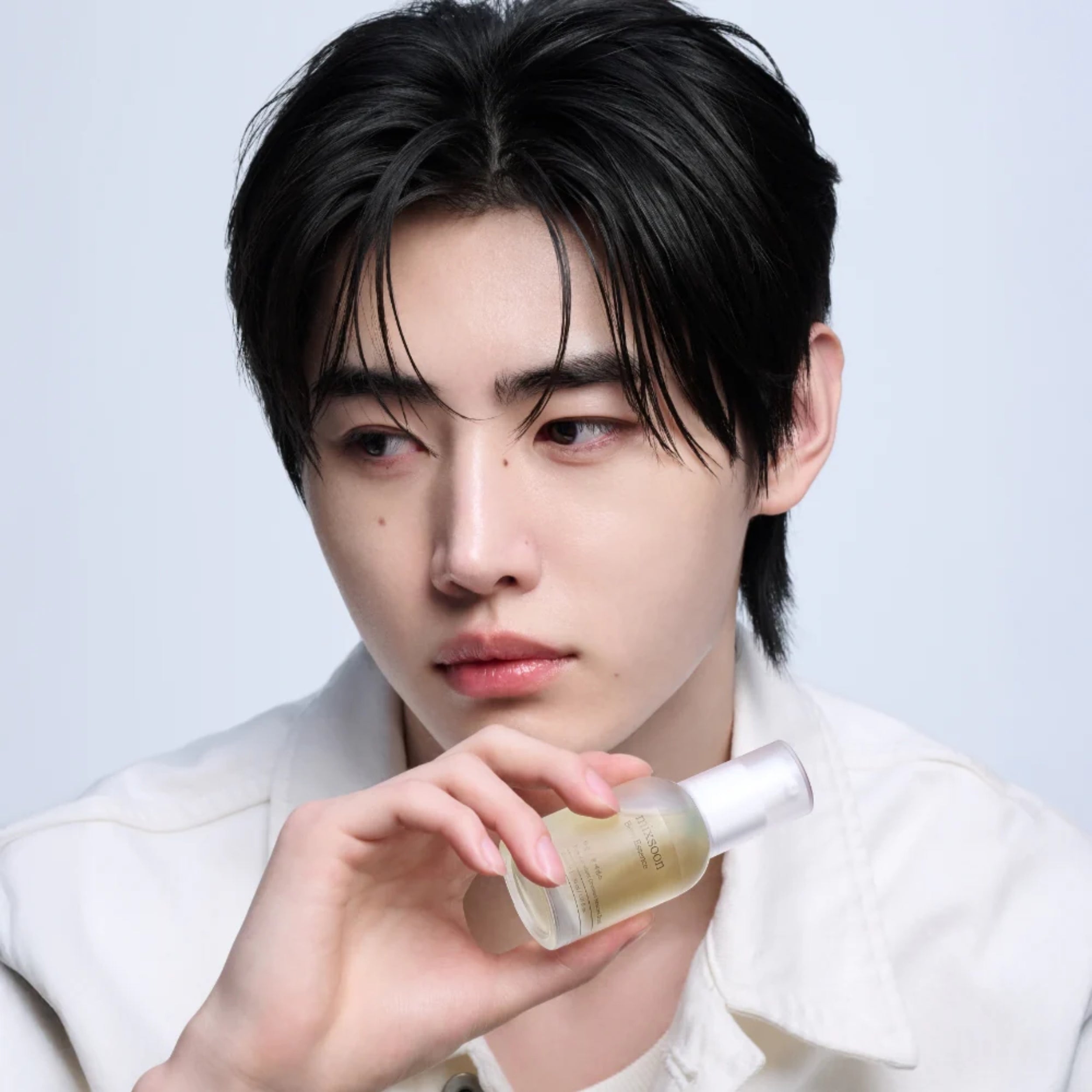 Person holding a skincare bottle against a plain background