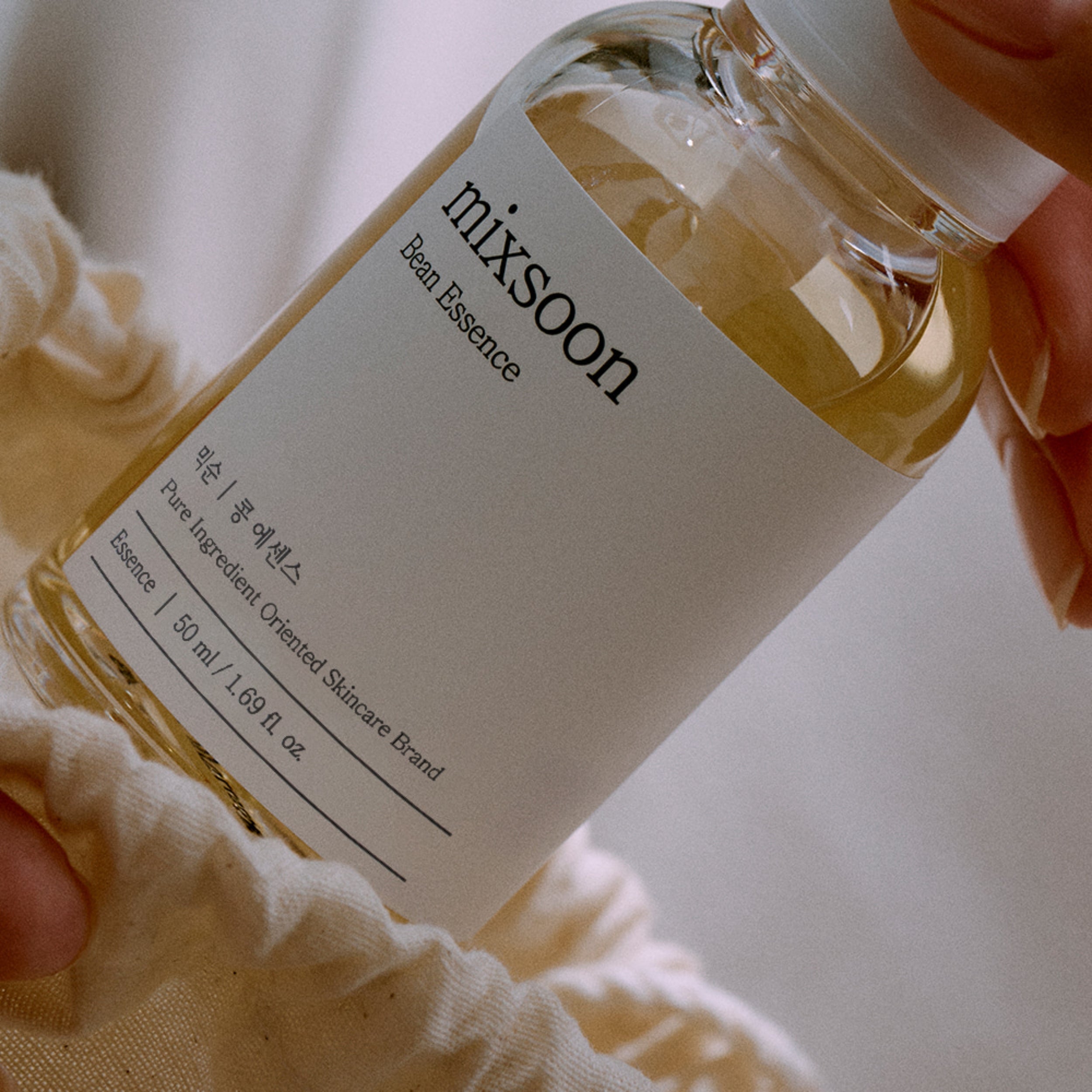 Bottle of Mixsoon Essence held by a person with a blurred background