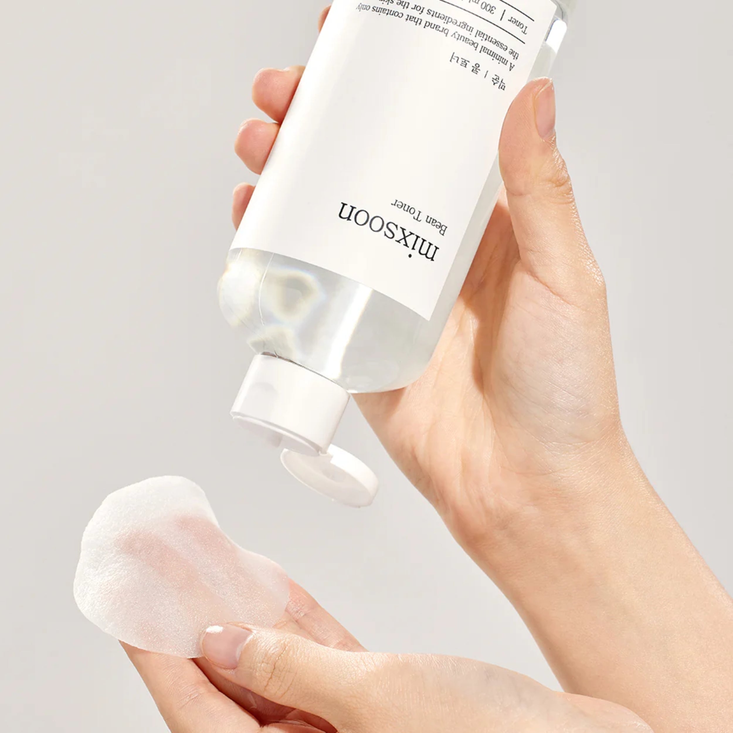 Hand holding a skincare product labeled 'mixsoon' against a neutral background