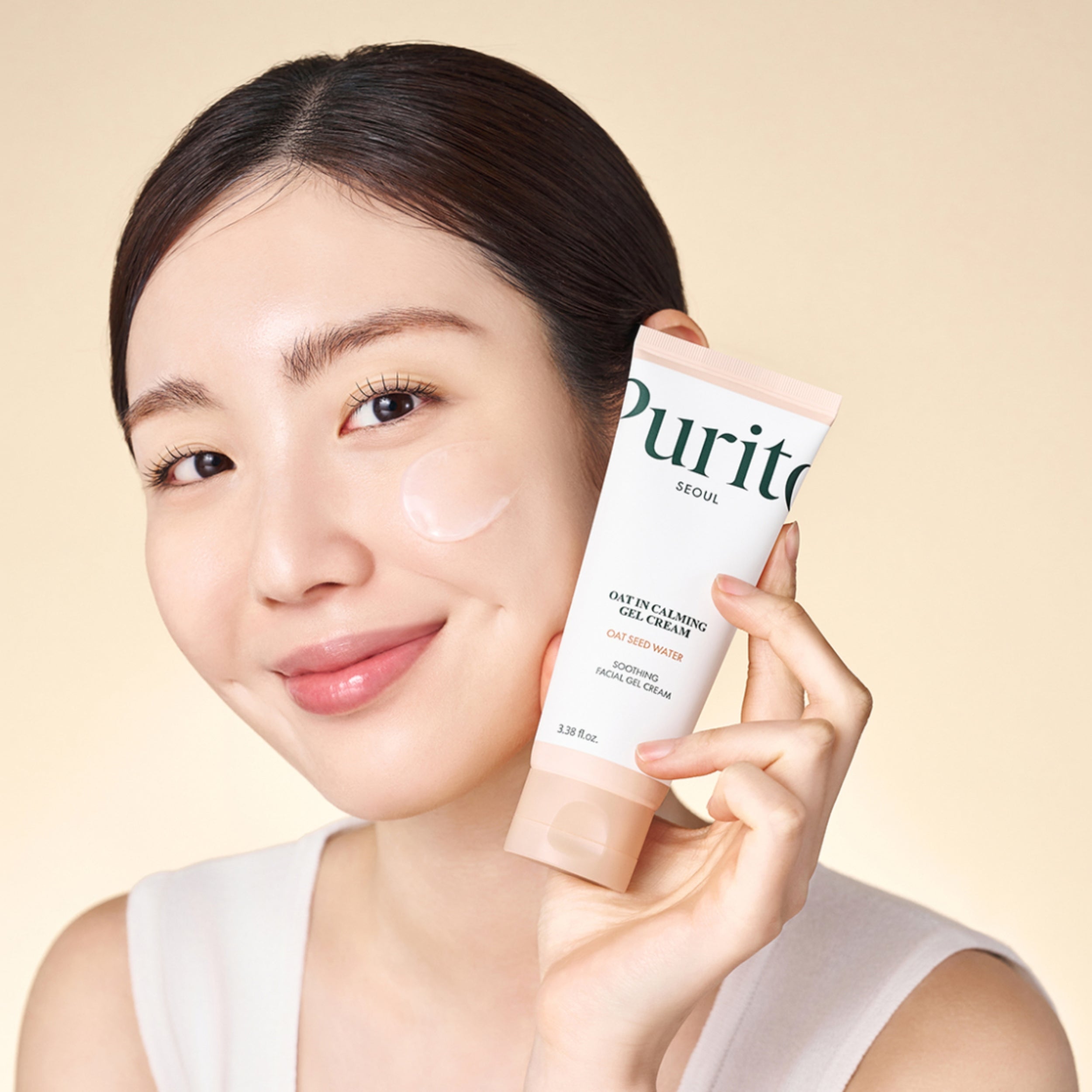 Woman holding a Purito skincare product against a beige background