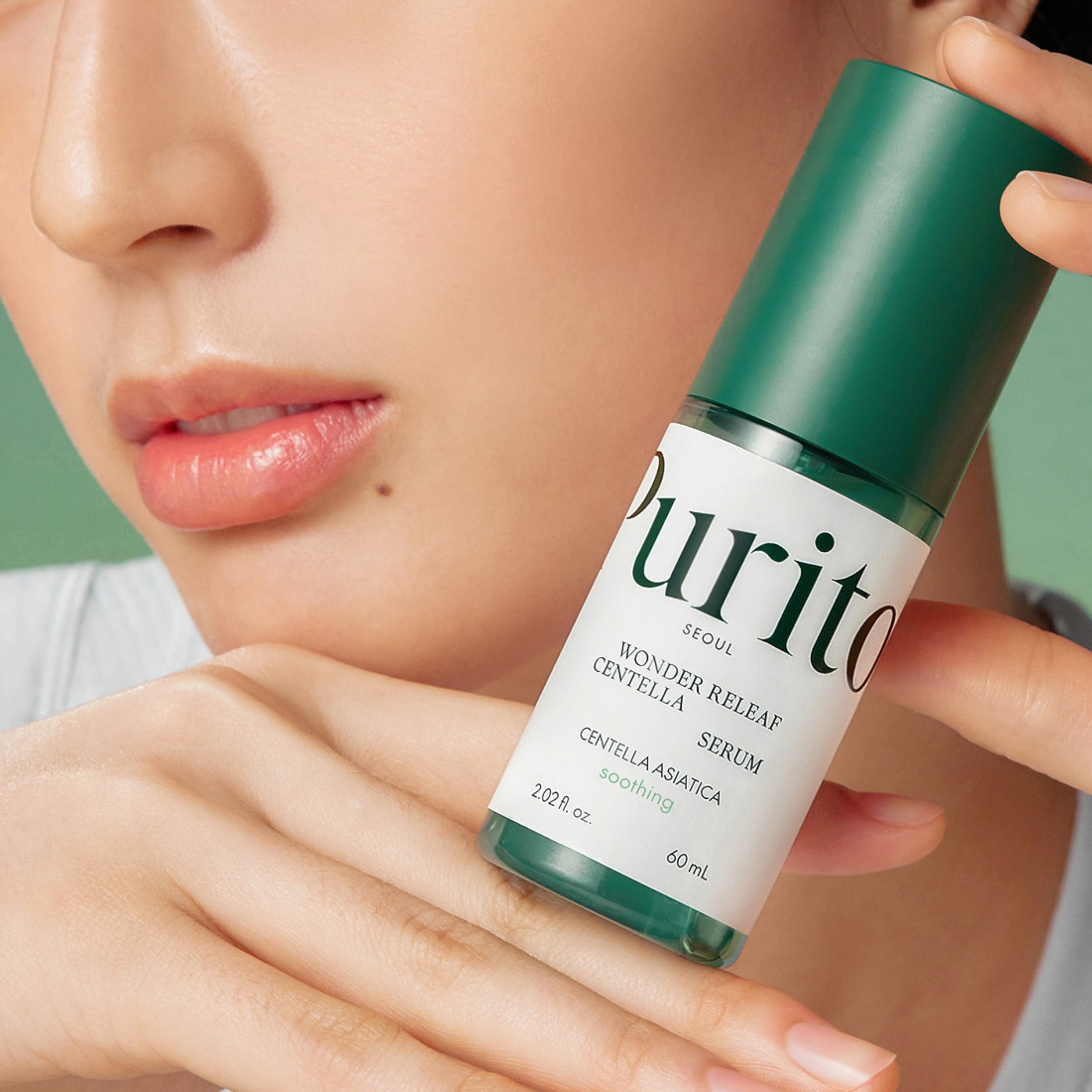 Person holding a Purito serum bottle close to their face