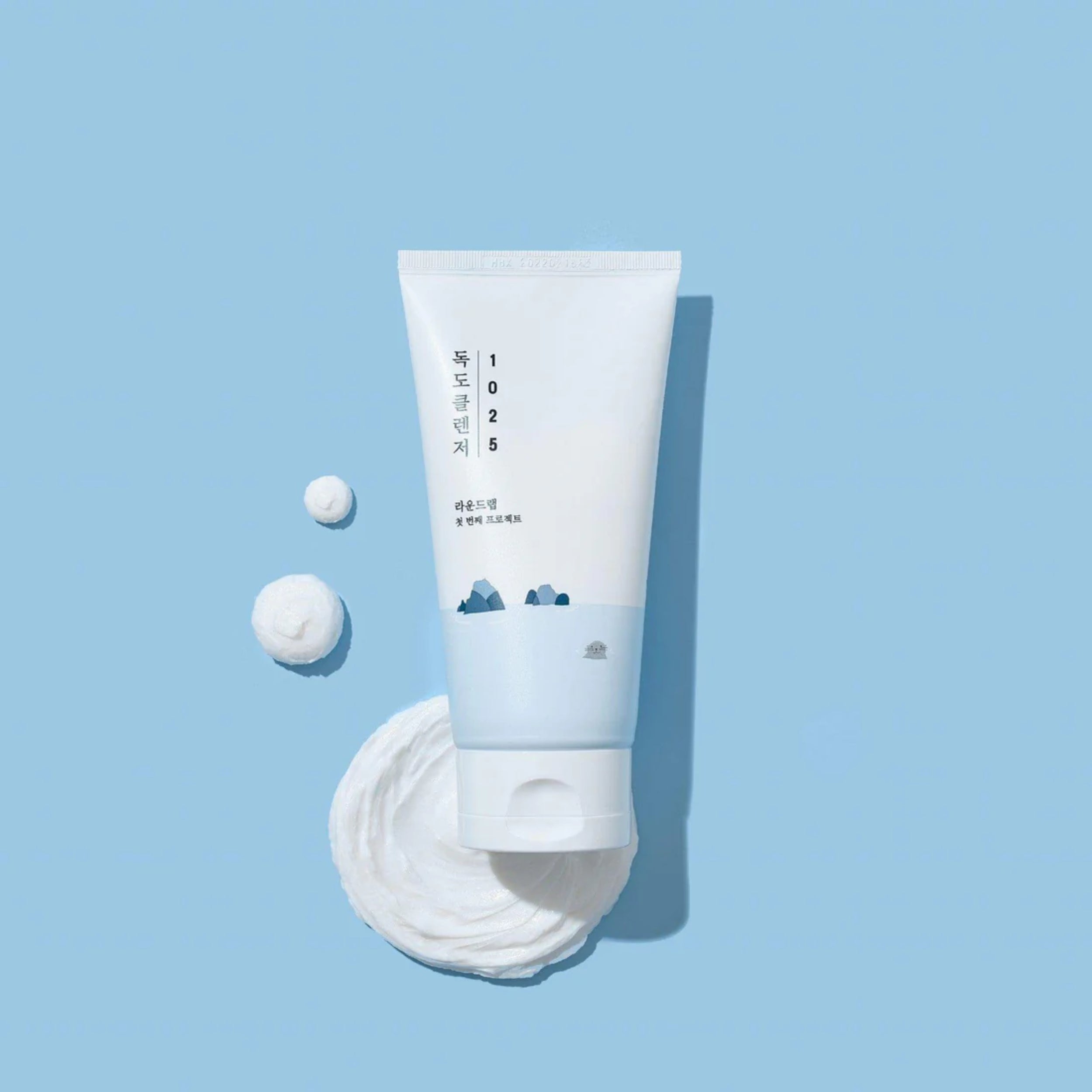 White skincare product with a small white ball on a light blue background
