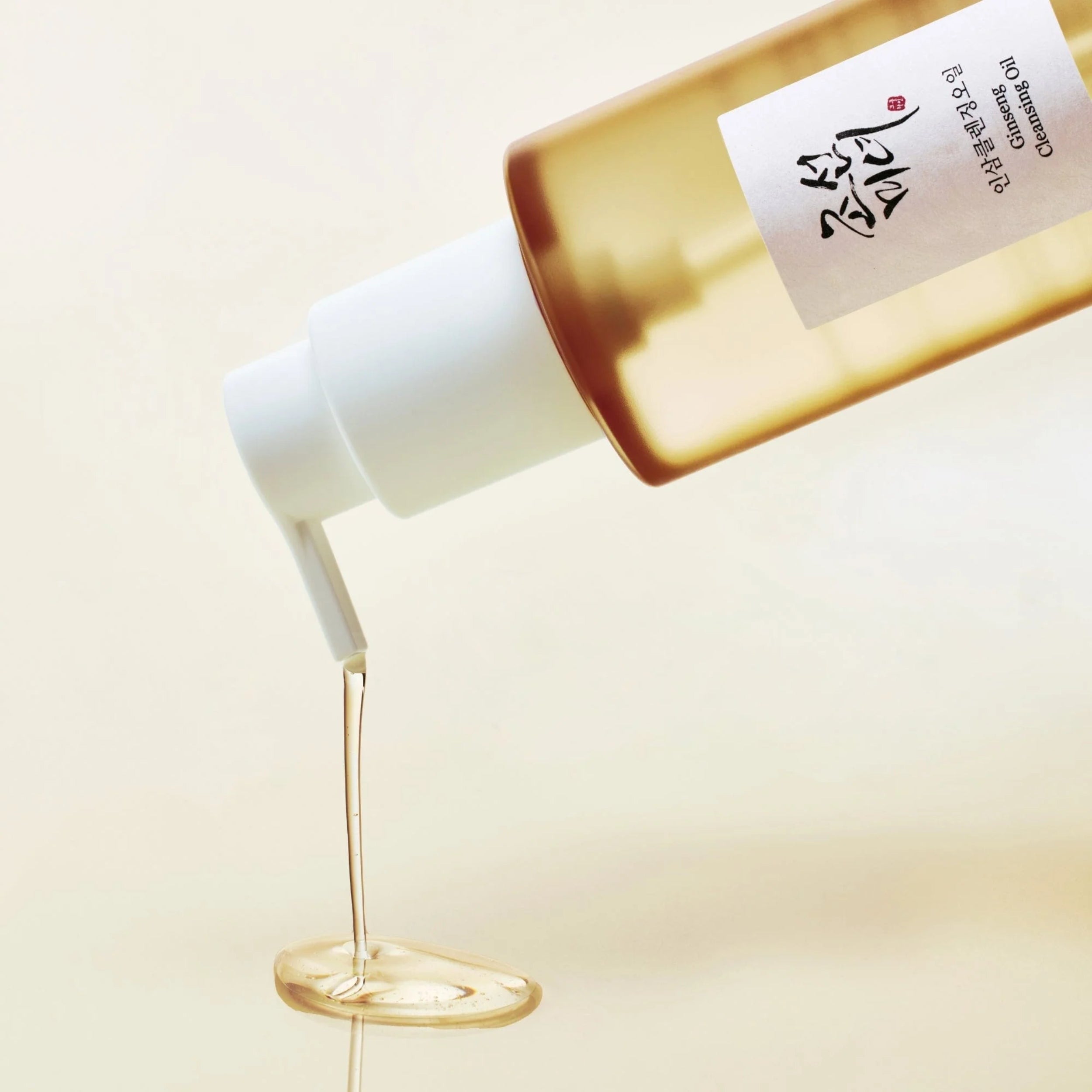 Skincare product with oil being poured onto a white container against a beige background