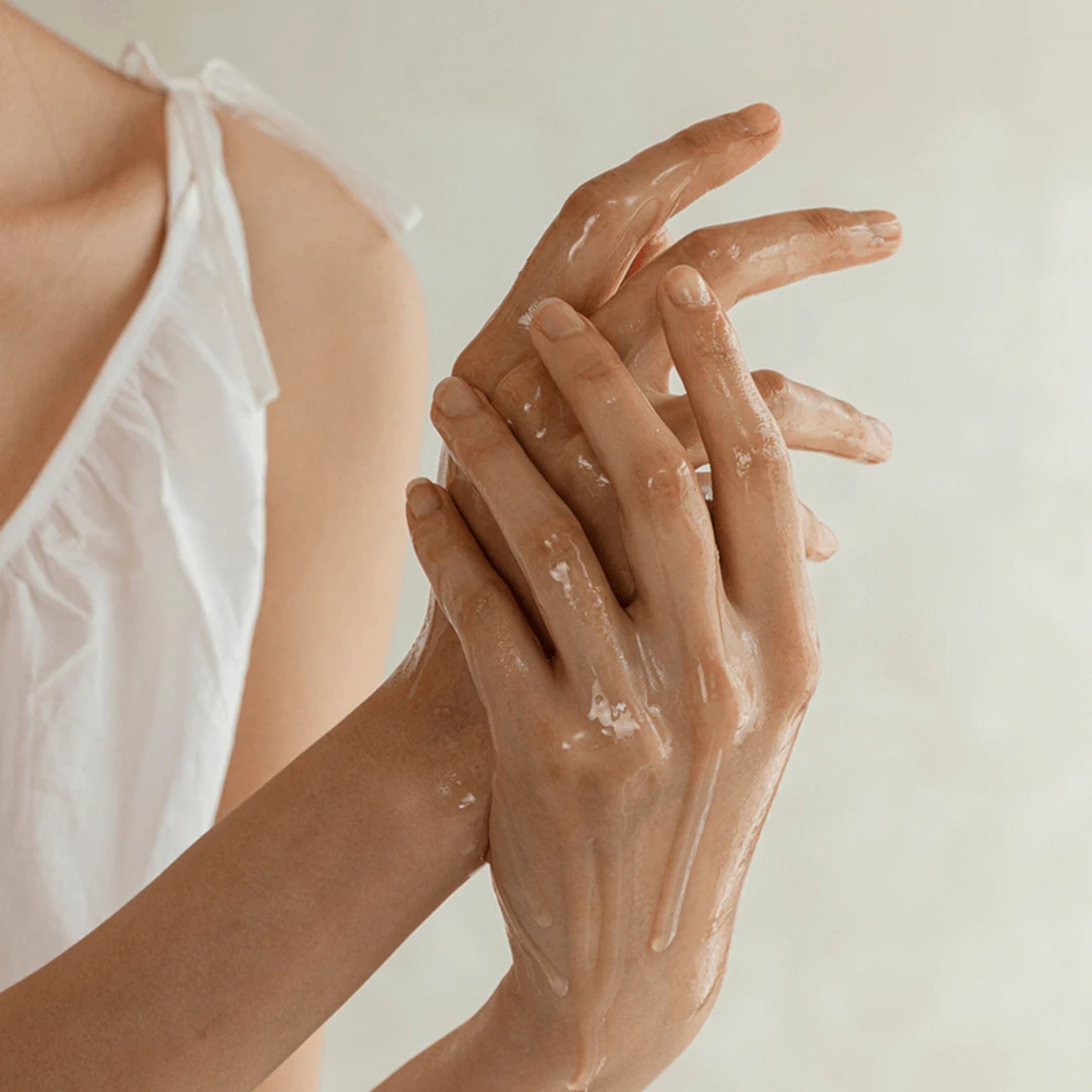 Person applying a Ginseng Cleansing oil to their hands with a neutral background
