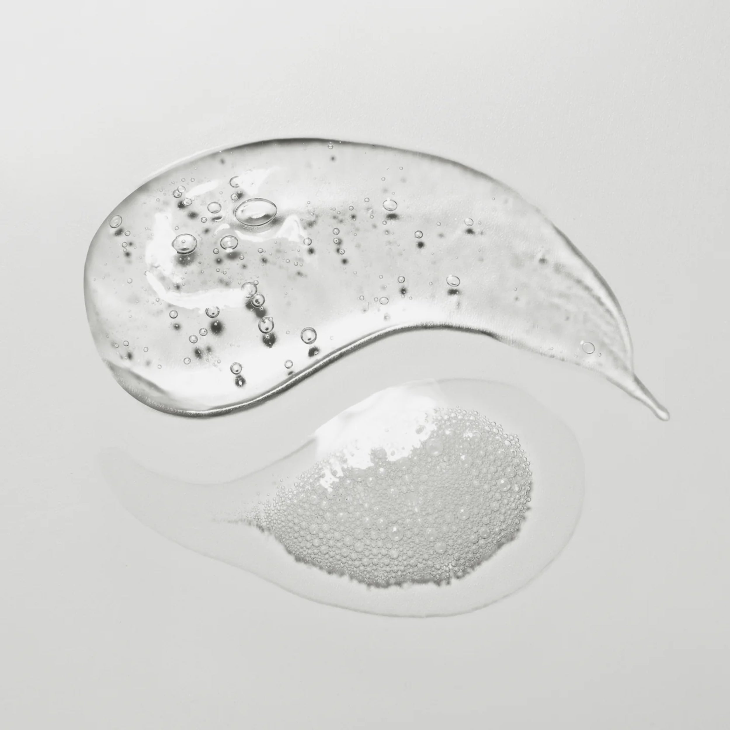 Close-up of a swirl of clear gel with bubbles on a light gray background