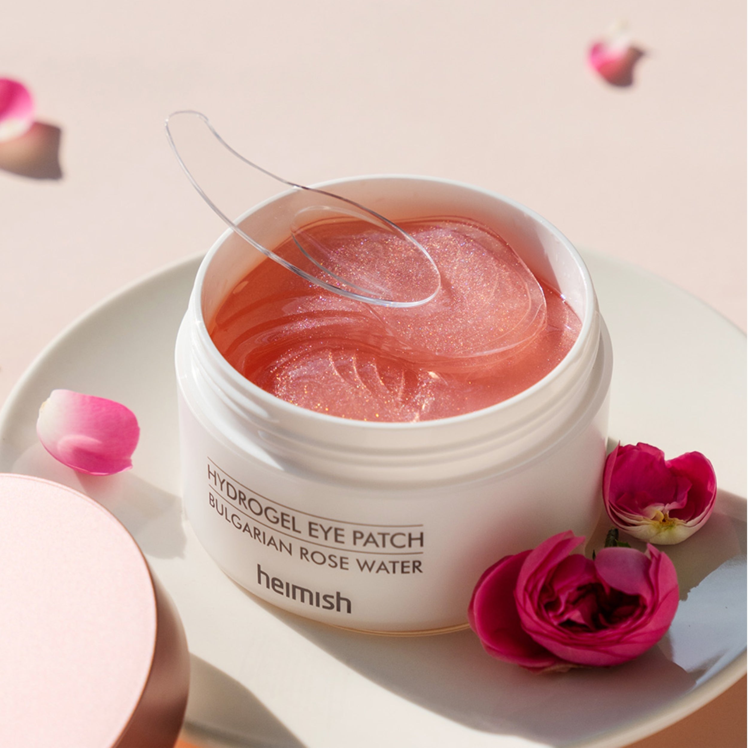 Jar of hydrogel eye patches with a spoonful of patches on a light background with flowers.