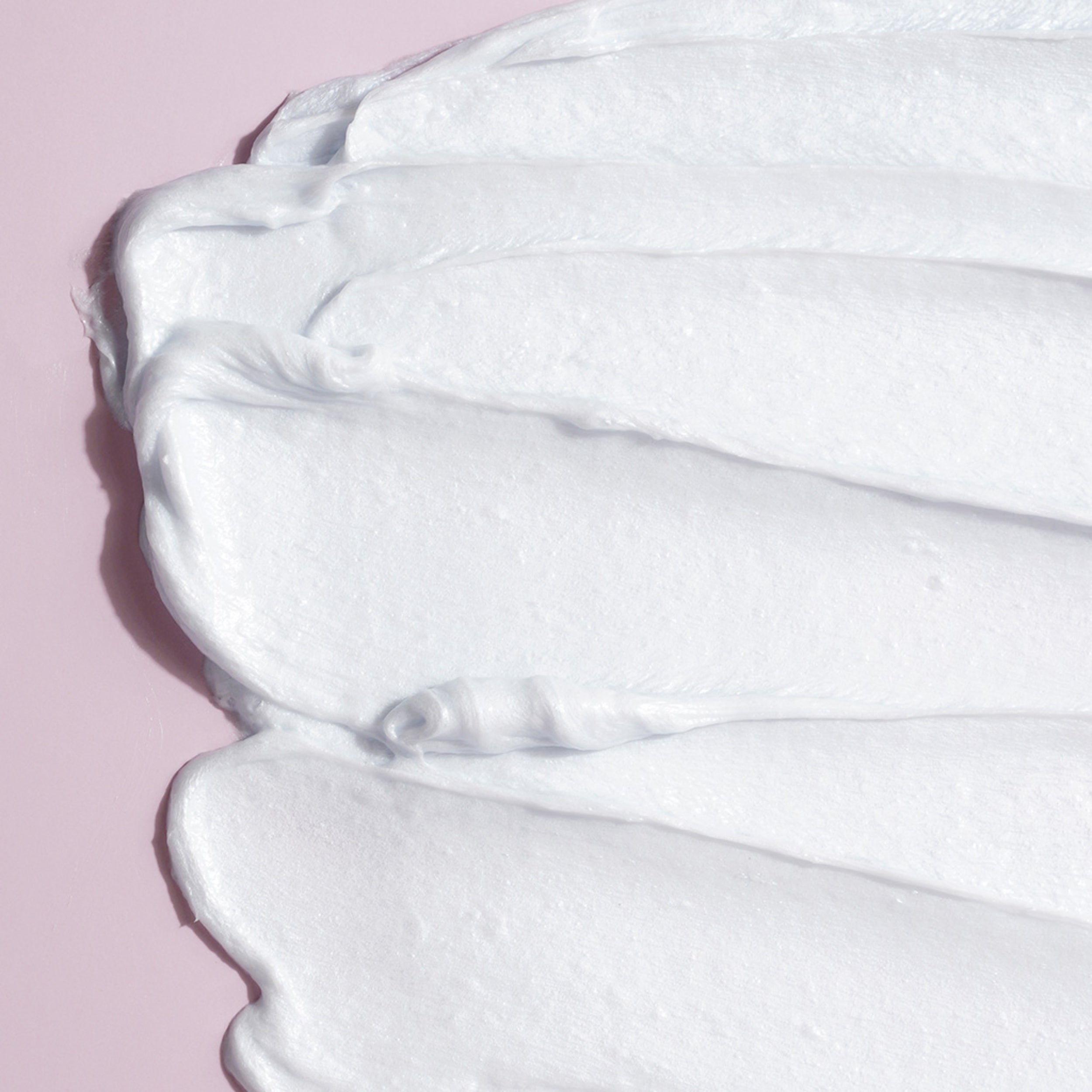 Close-up of white cream or lotion on a pink background