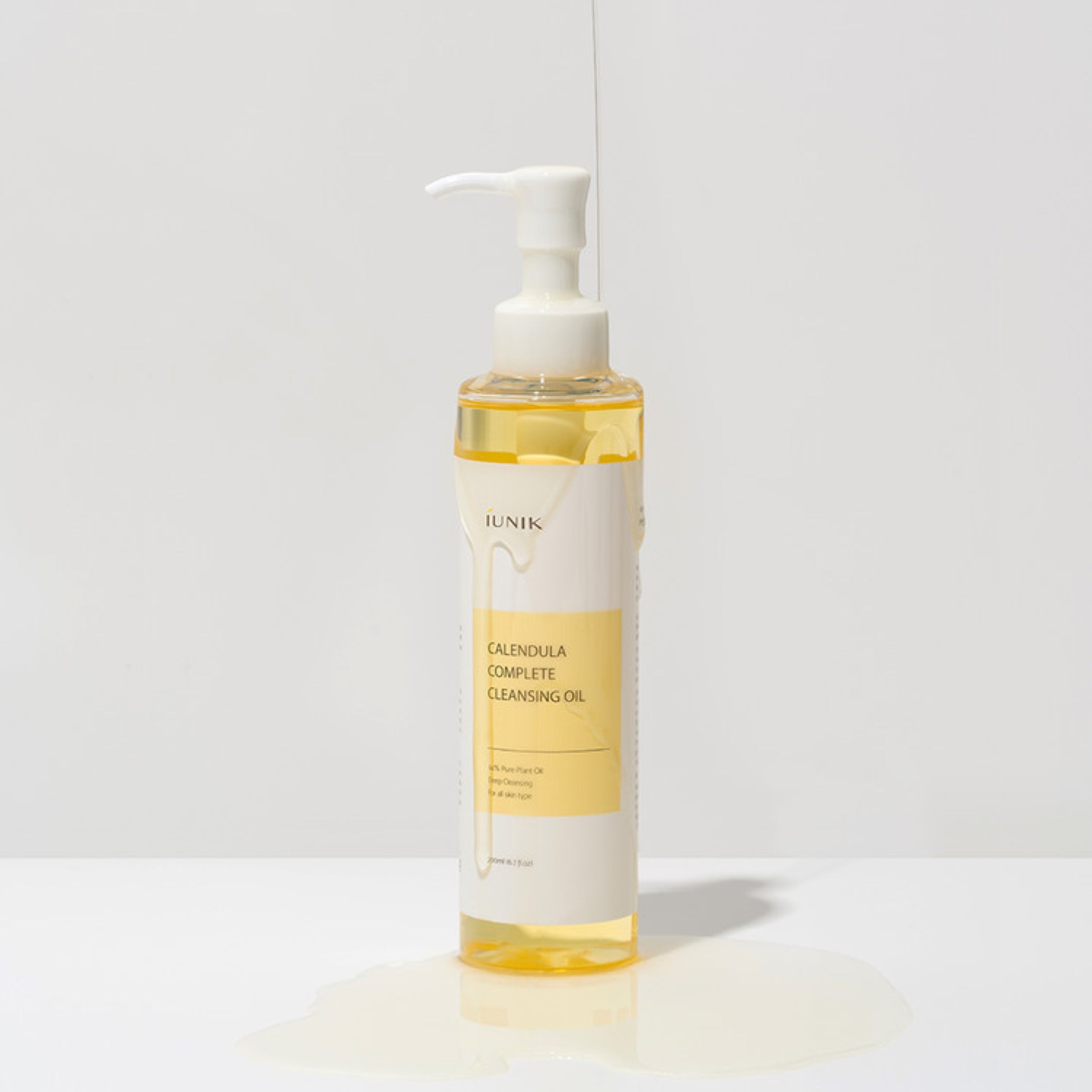 Bottle of Calendula Complete Cleansing Oil with pump on a light gray background