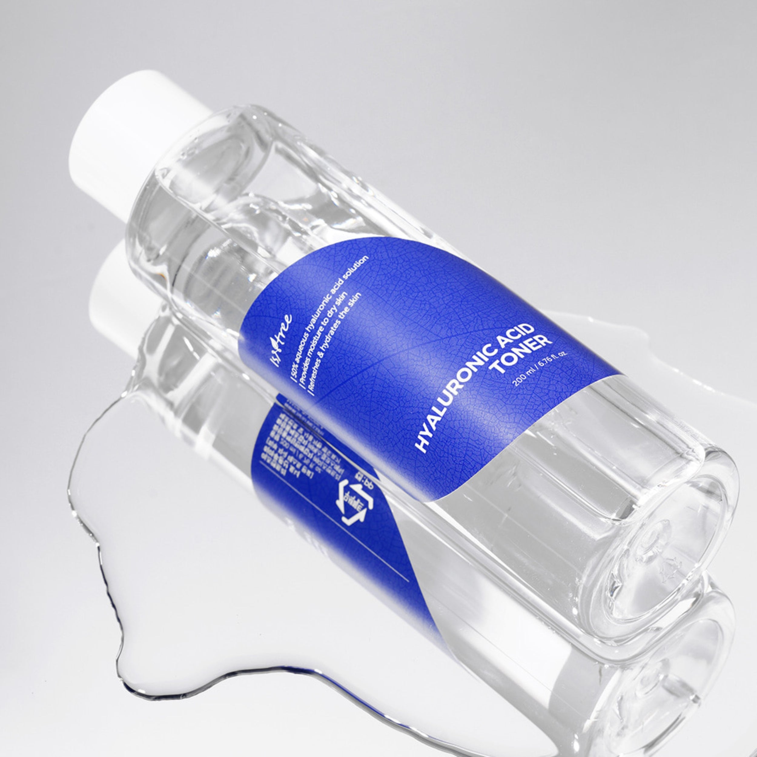 Clear bottle of hyaluronic acid toner with a blue label on a light gray background