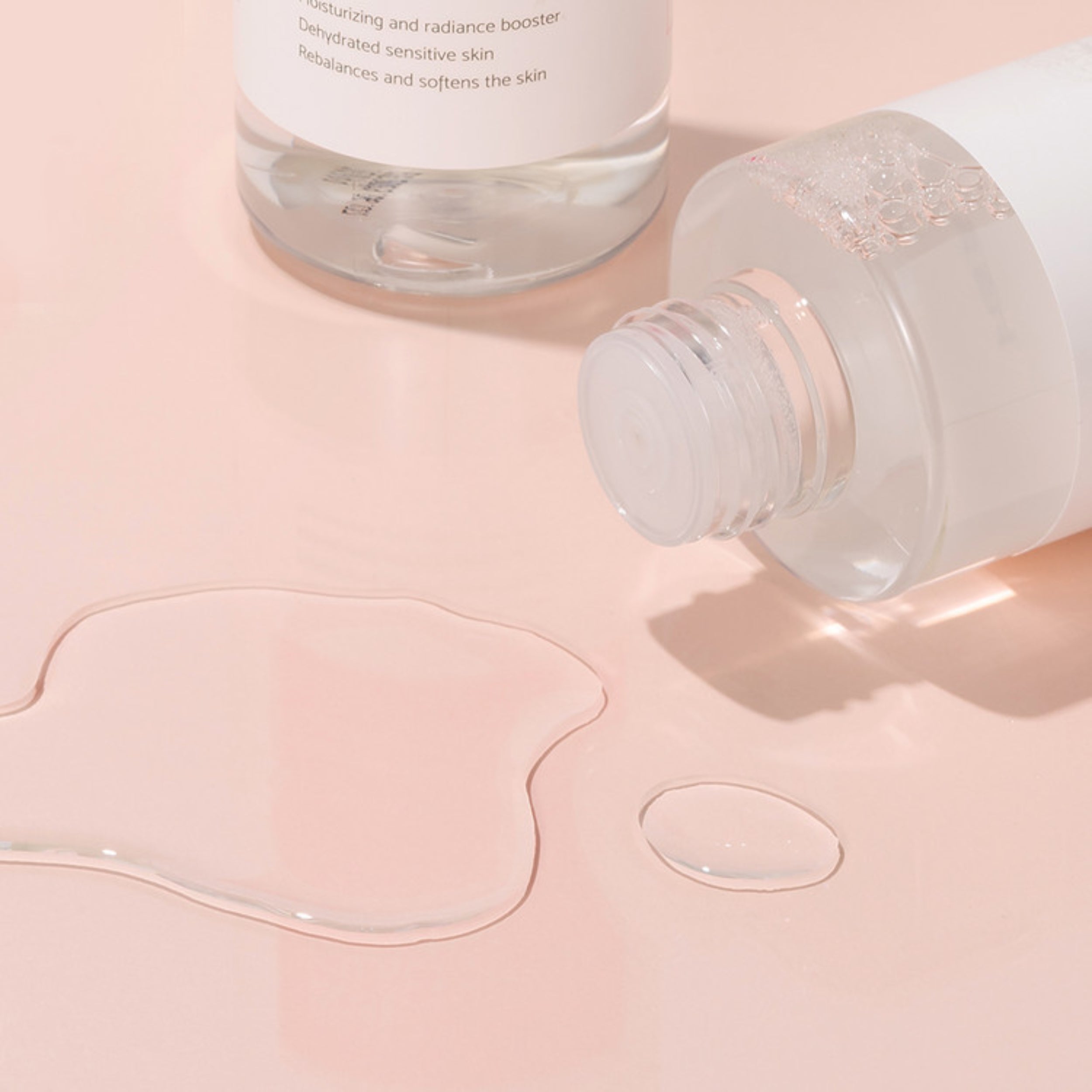 Skincare product with droplets on a pink surface