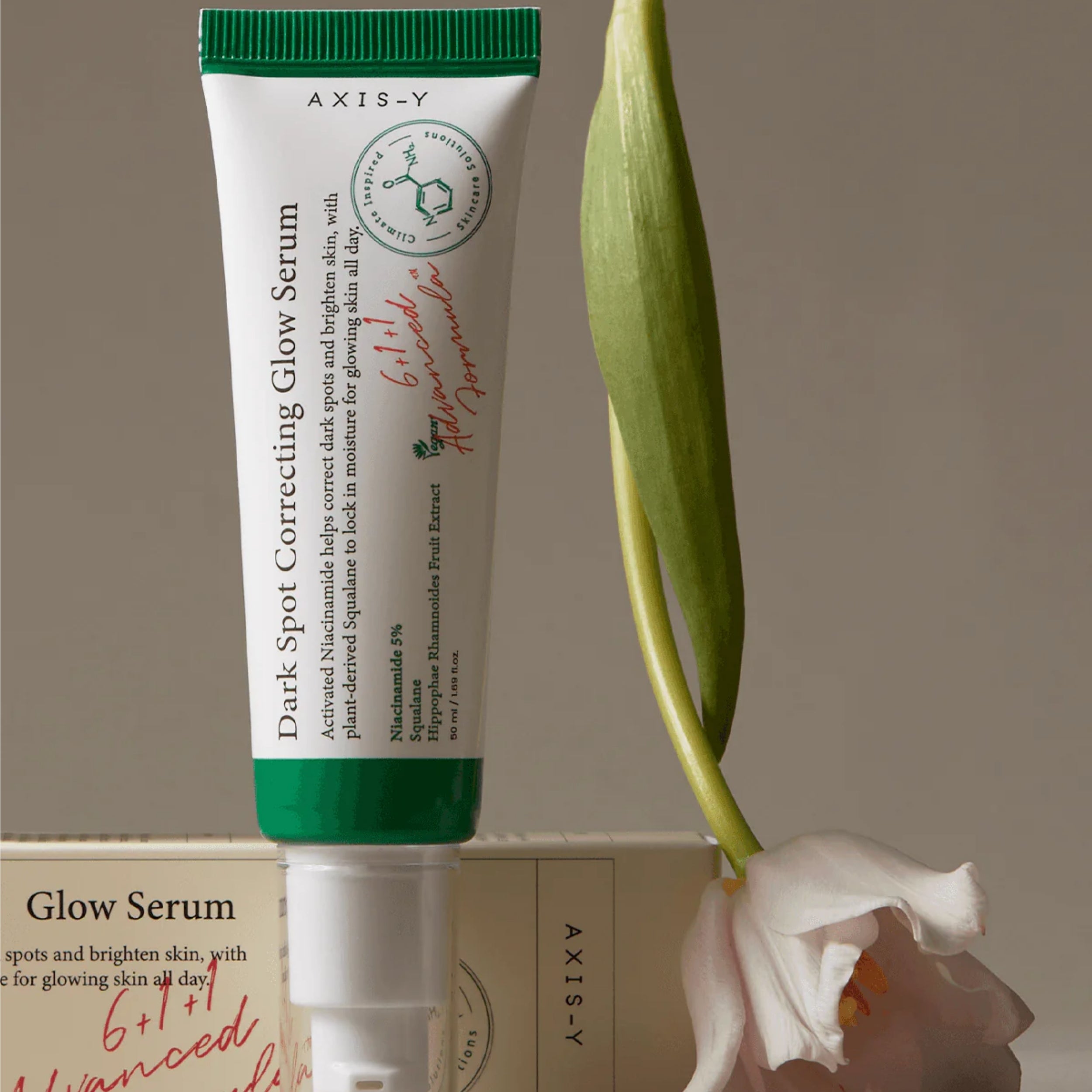 AXIS-Y Dark Spot Correcting Glow Serum with a flower on a neutral background