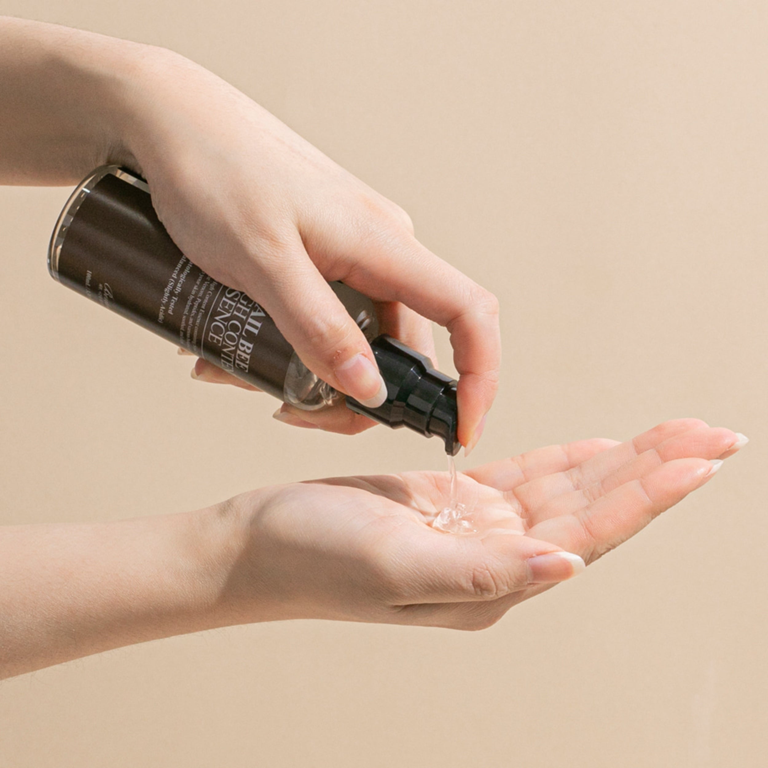 Hand holding a Benton essence bottle over another hand on a beige background