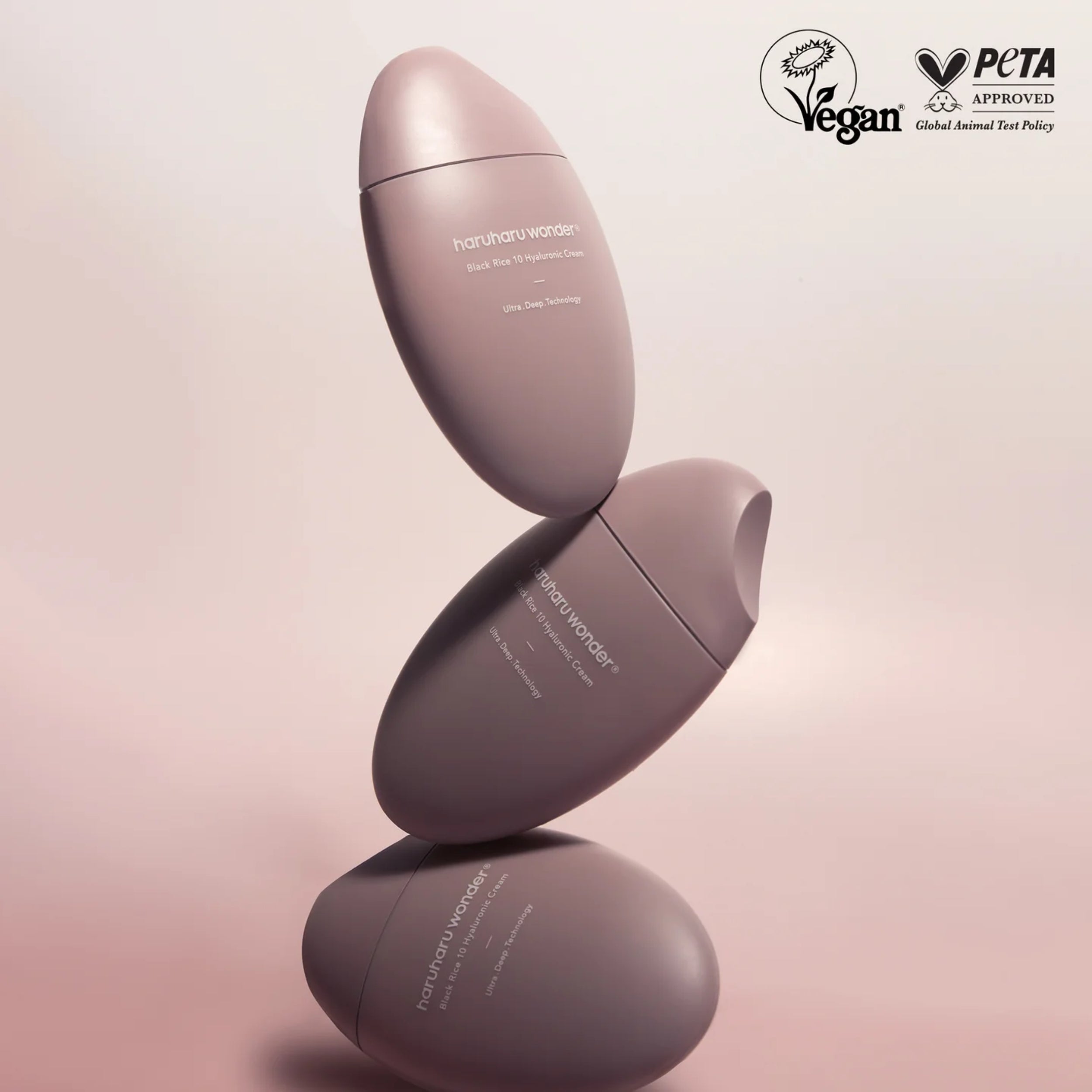 Two pink skincare bottles stacked on a light pink background with PETA approval logo.