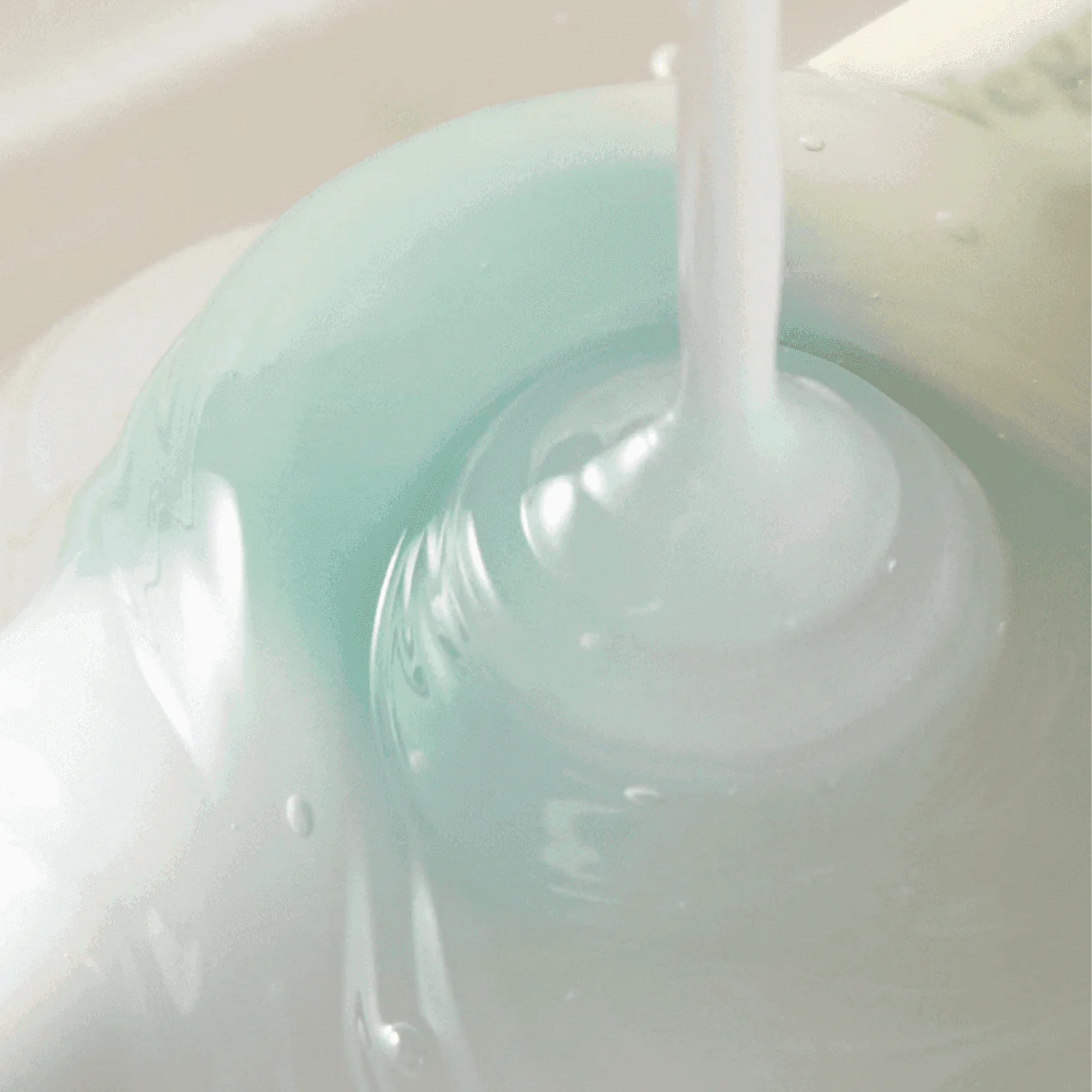 Close-up of a light blue liquid being poured into a container.