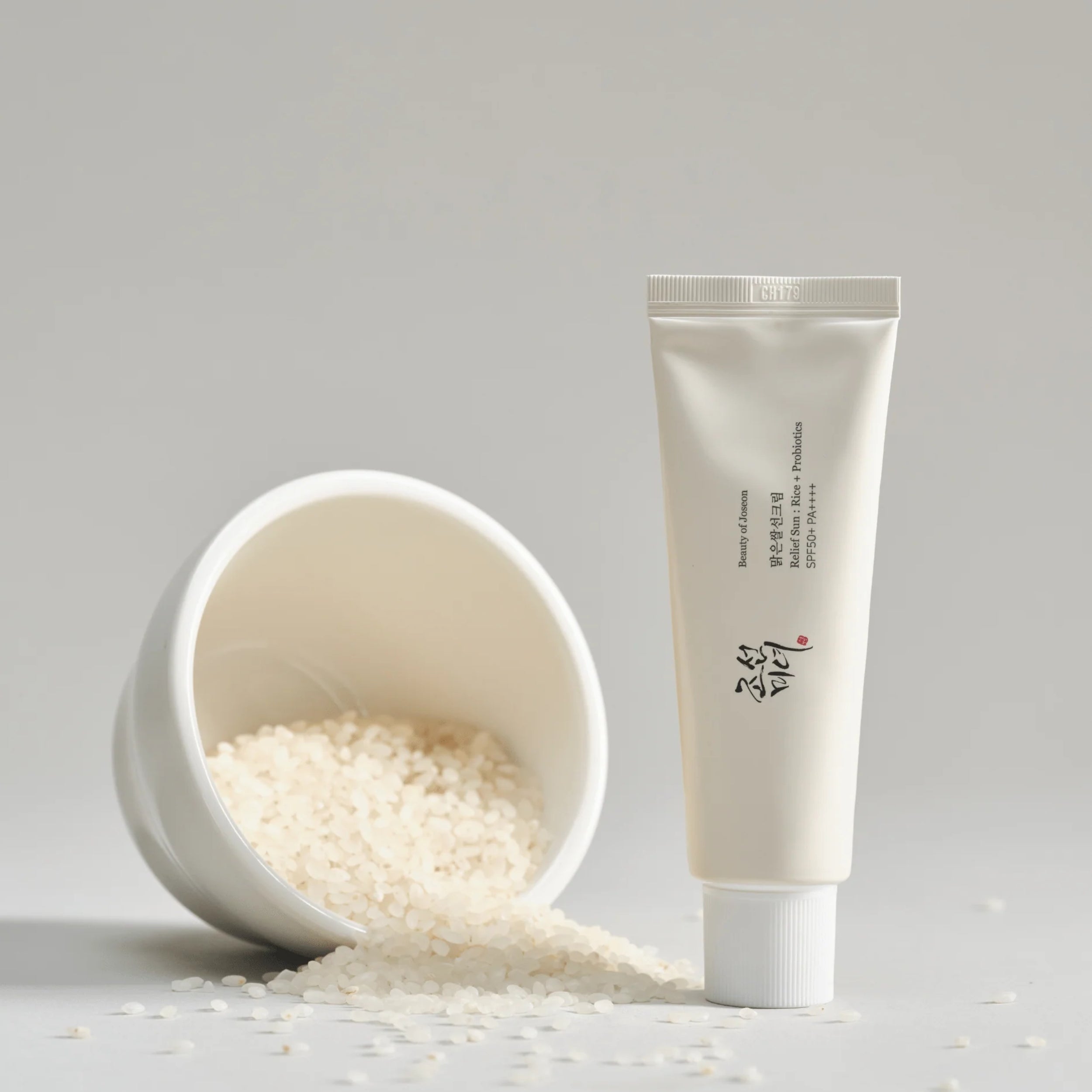Tube of cream next to a bowl of rice on a light gray background