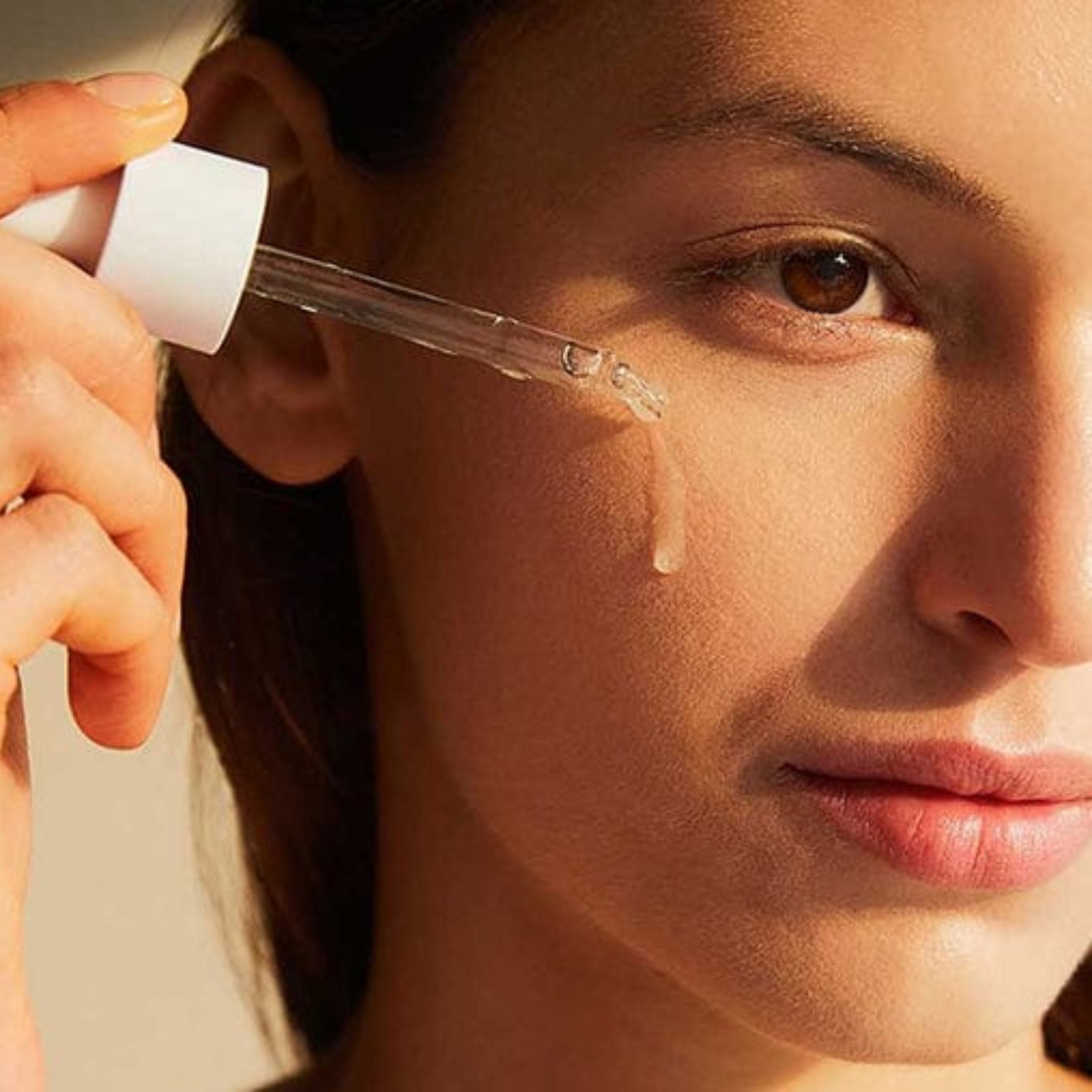 Person applying a dropper of liquid to their face