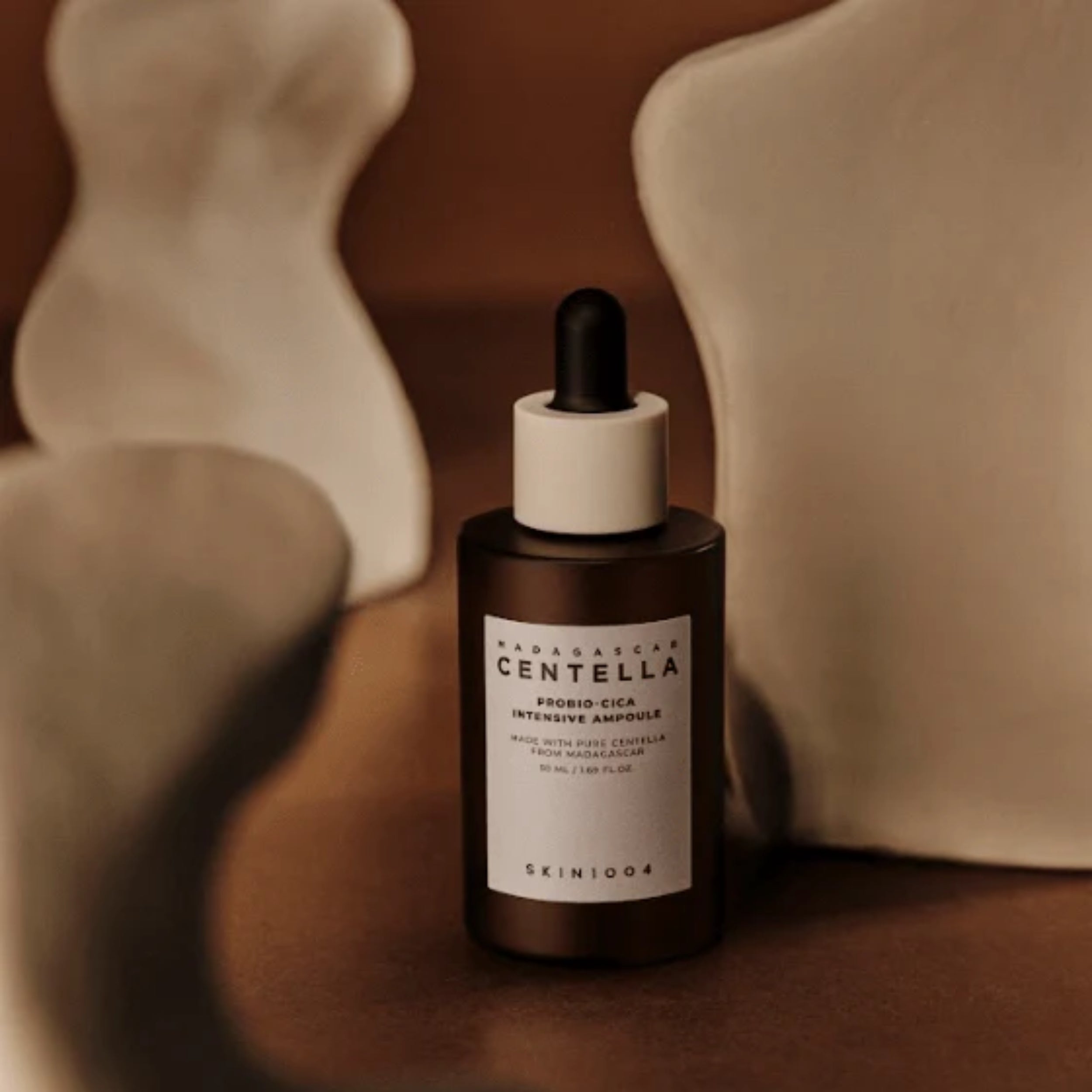 Skincare dropper bottle with 'Madagascar Centella' label on a brown background