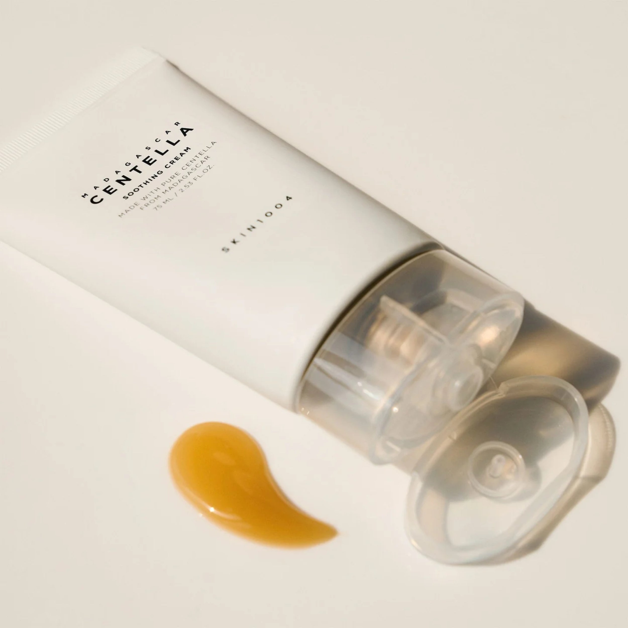 Skincare cream tube with a visible droplet of cream on a light background