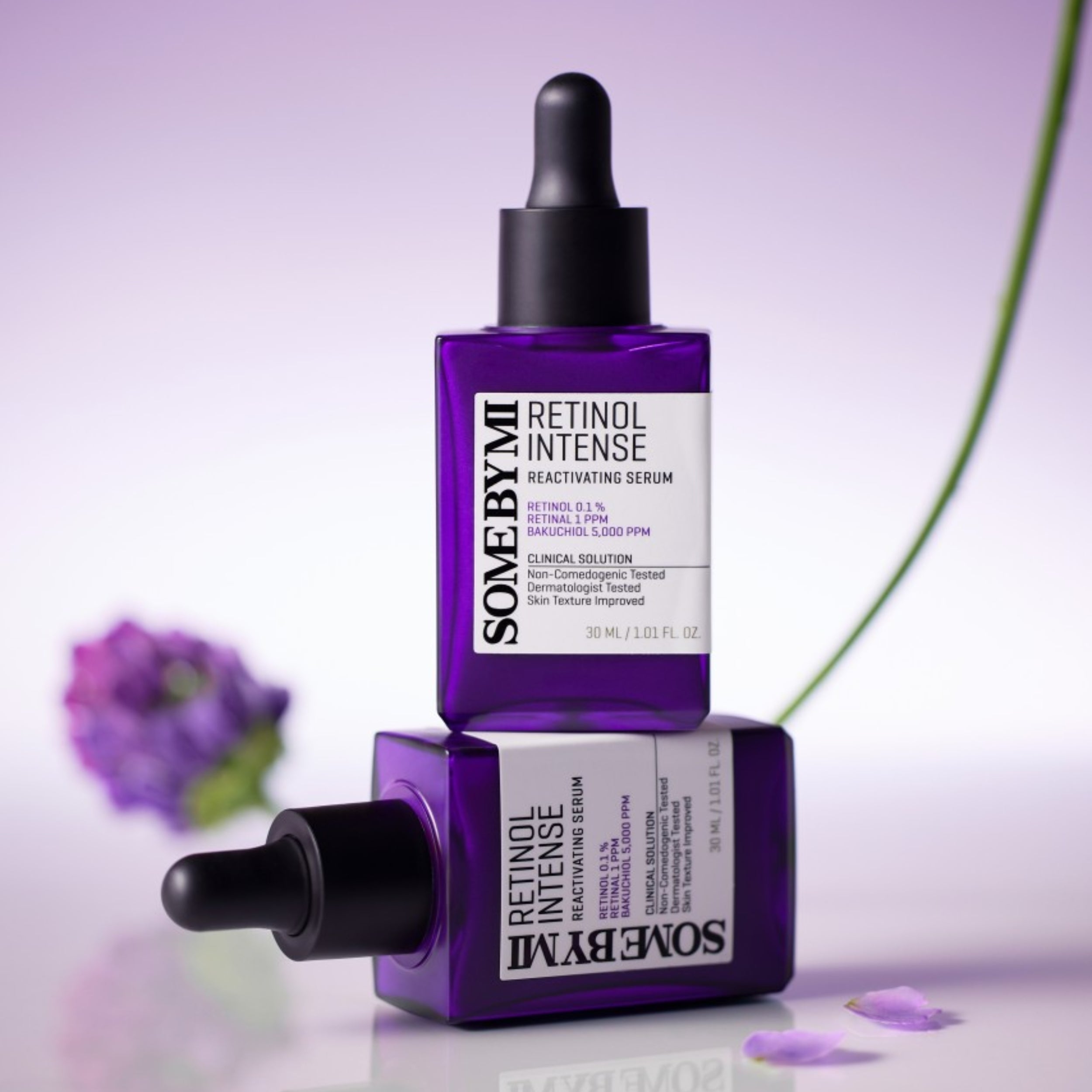 Two purple bottles of SOMEBYMI Retinol Intense serum on a light purple background with a flower.