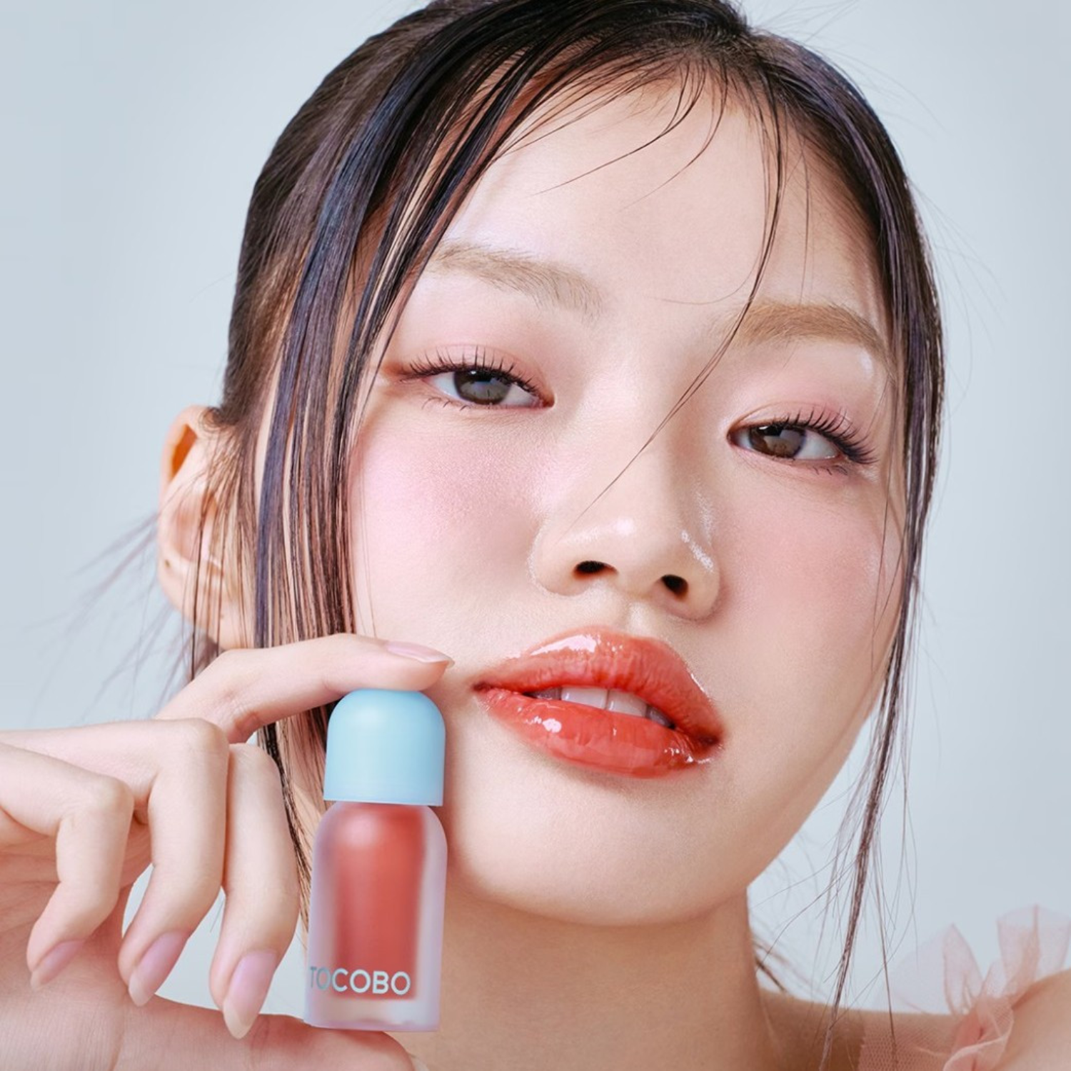 Woman holding a lip balm of TOCOBO with a neutral background