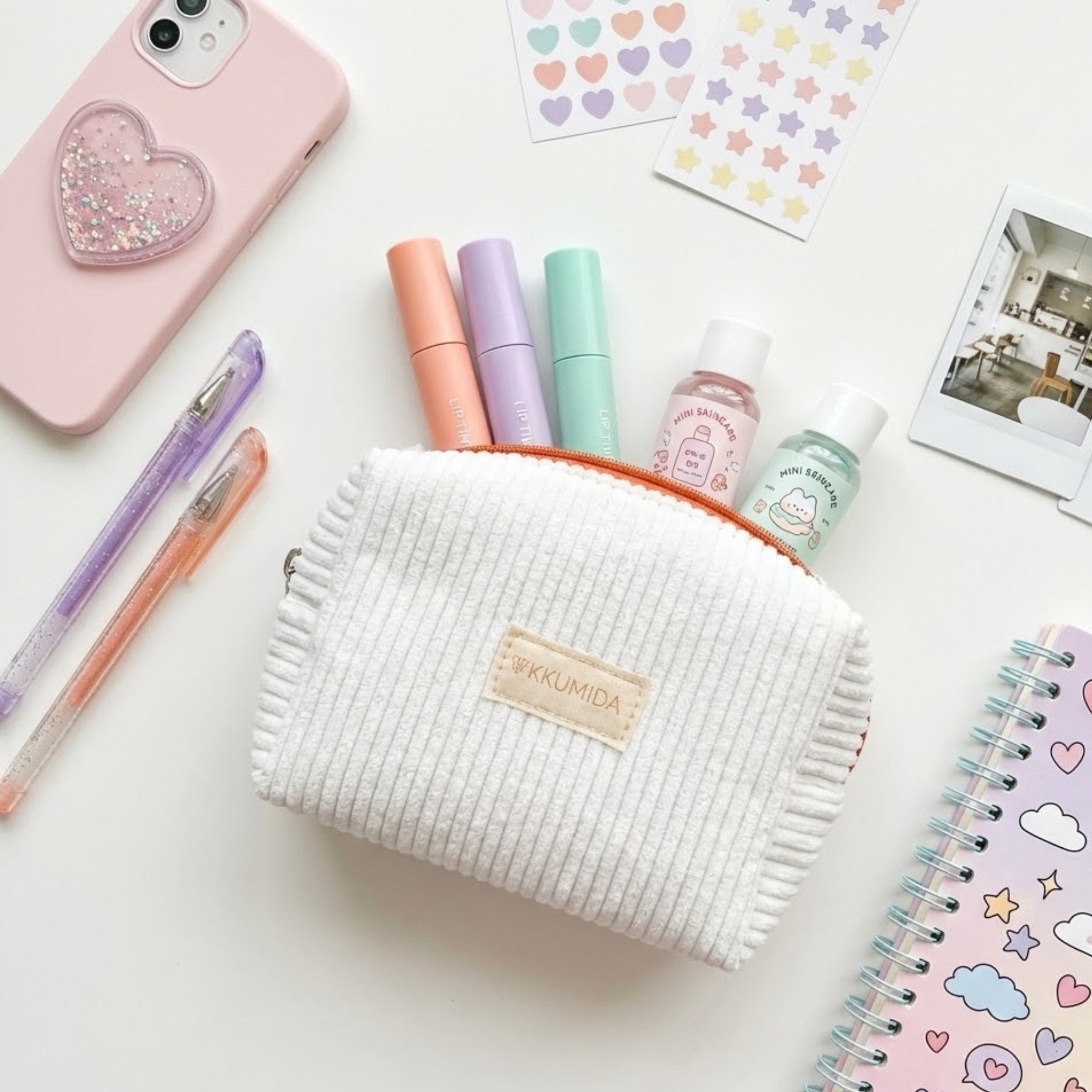 White textured pouch with 'Yukkumida' branding, phone, pens, and stationery items on a white background