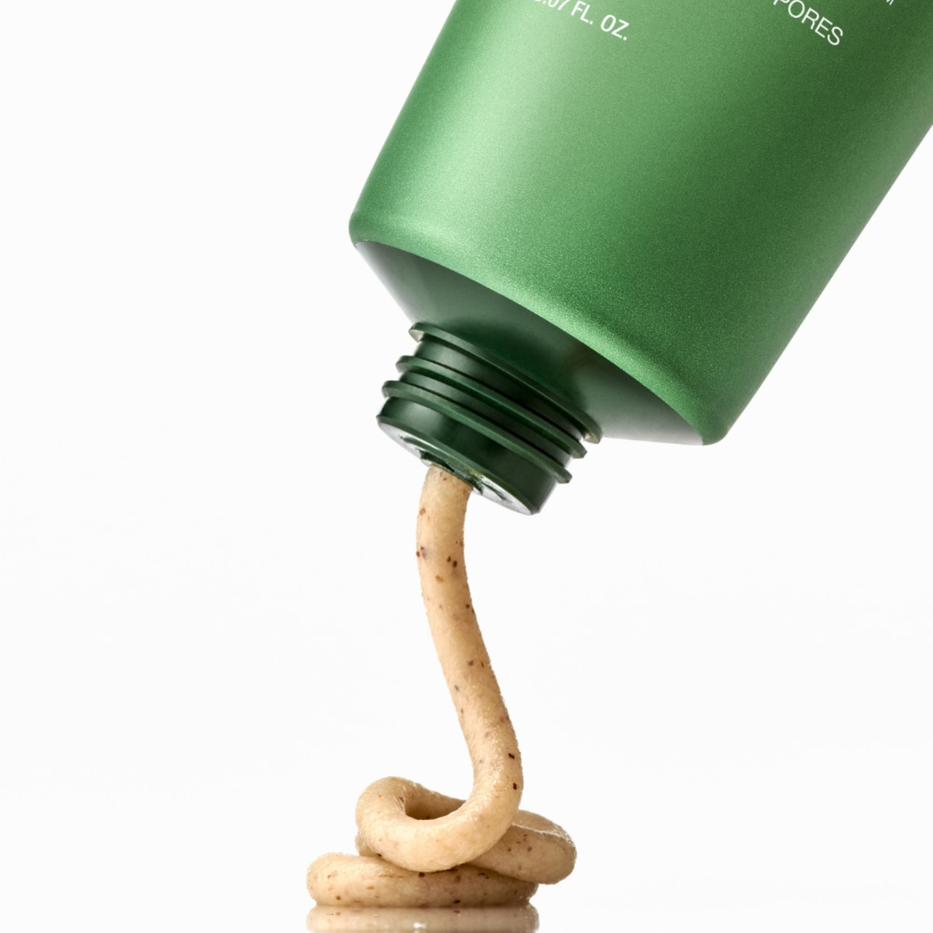 Green bottle cap with a stream of beige product flowing out on a white background