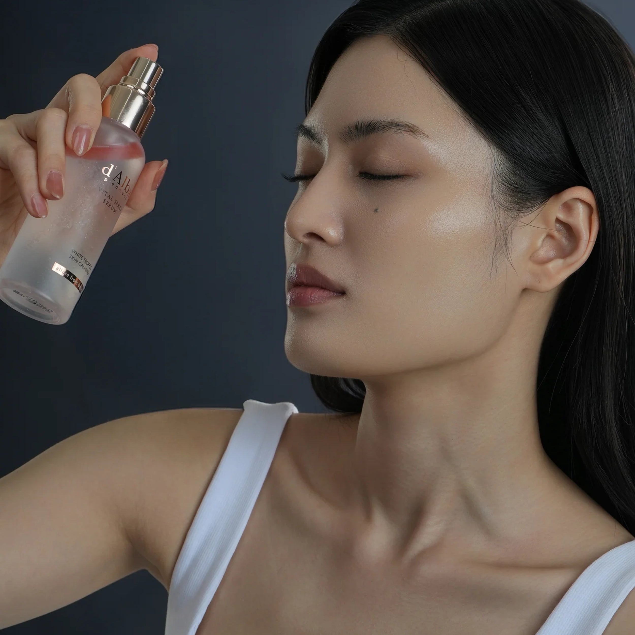 Woman receiving a skincare treatment with a dropper bottle against a dark background