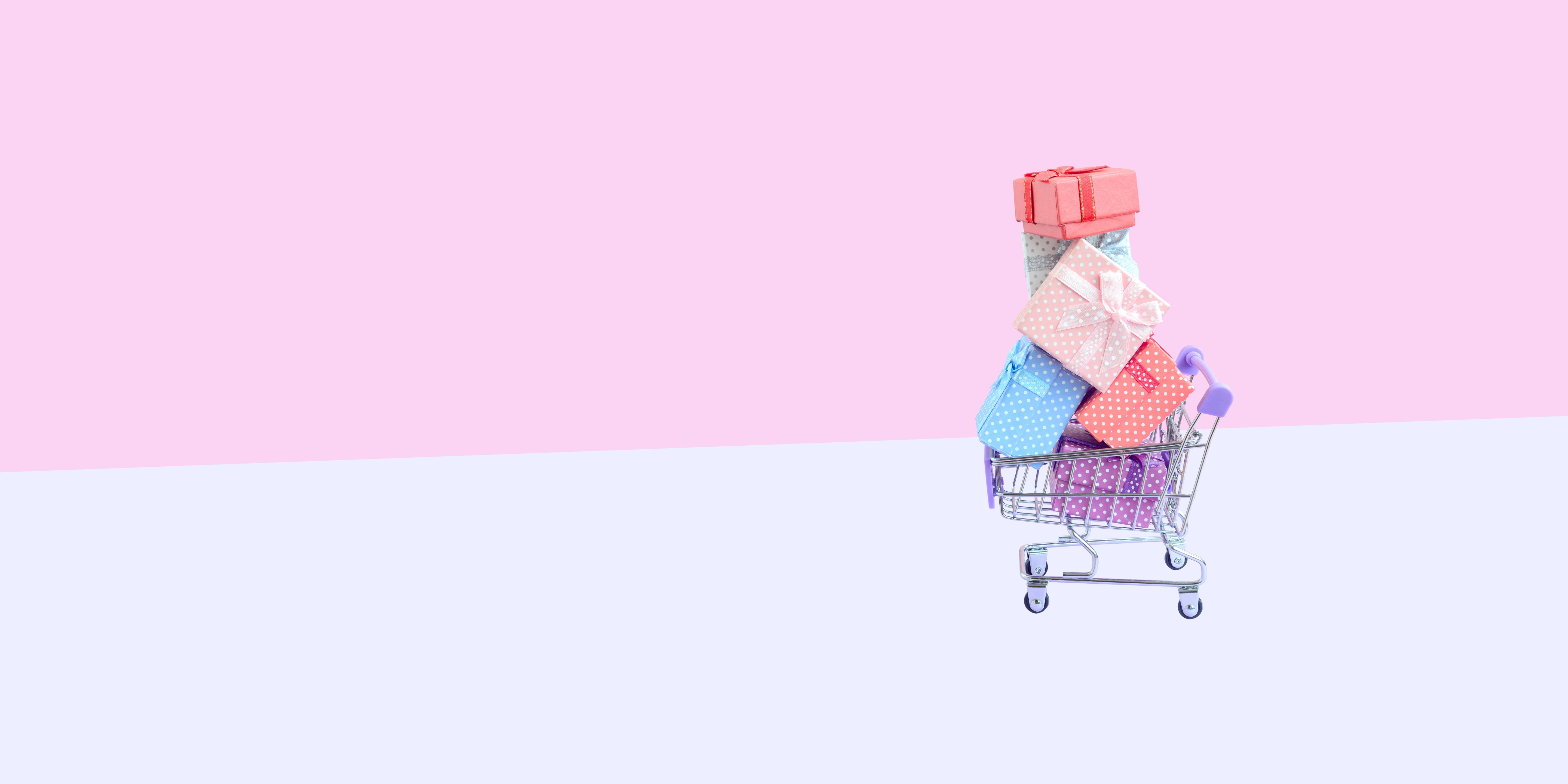 Person in a shopping cart with gifts on a pink and white background