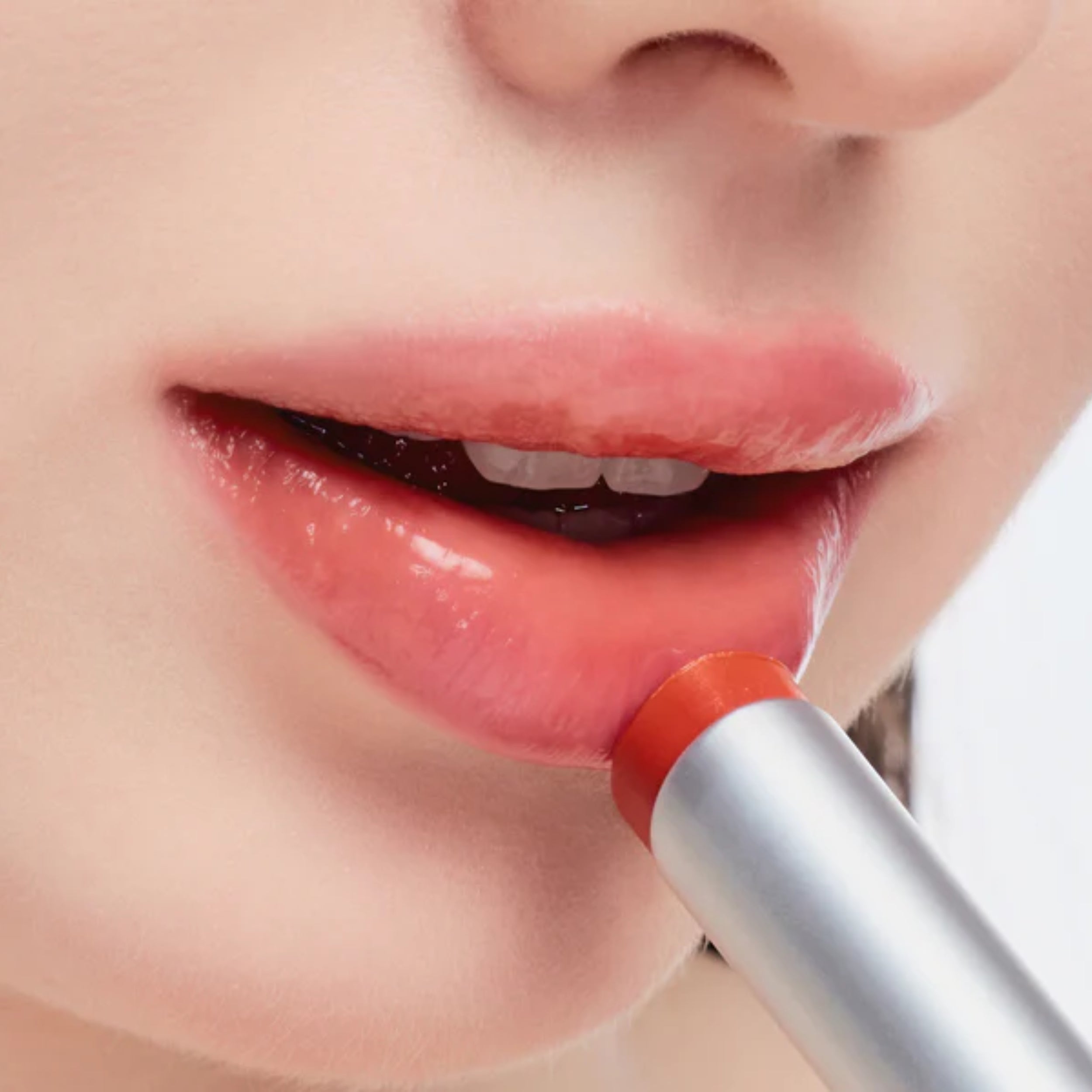 Close-up of a person applying red lipstick with a silver applicator.